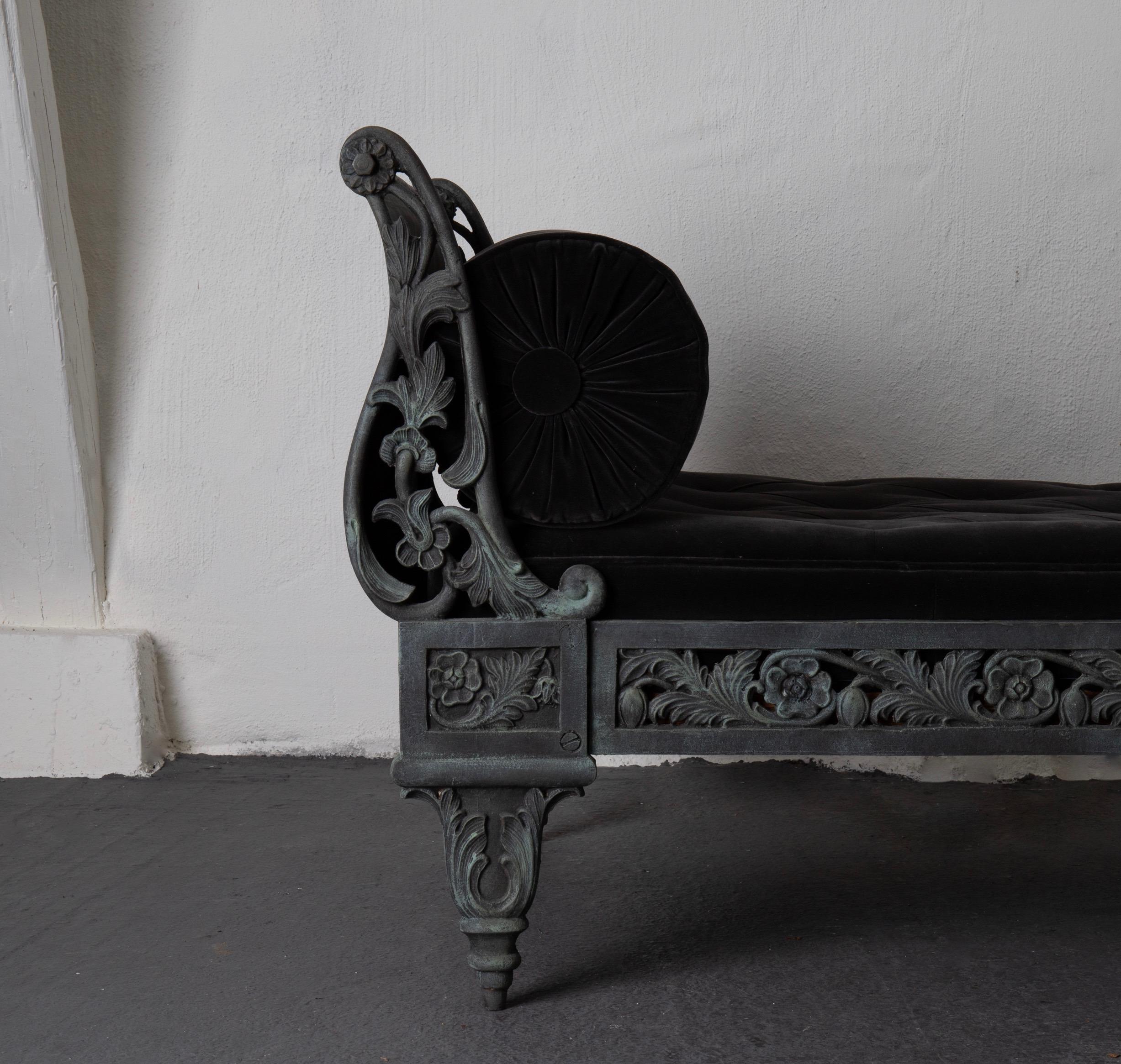 A cast iron daybed in an oxidized green color. Made during the 19th century, late Empire period in France. All in cast iron with cushion and bolster in dark gray velvet. Frame decorated with flowers and leaves - would go perfectly on a porch or in a