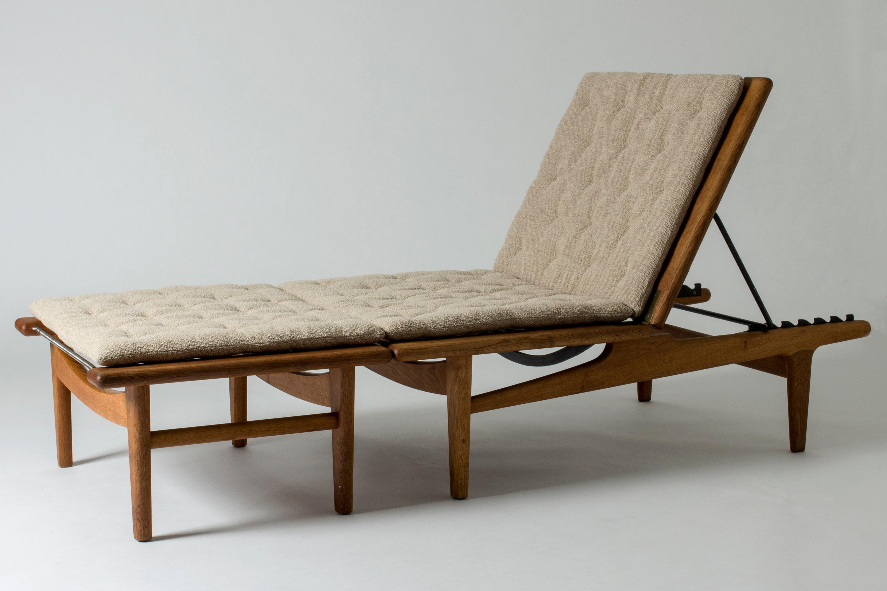 Very cool lounge chair with footstool by Hans J. Wegner. Can be set in a flat position and turned into a daybed. Made from oak with beautiful woodgrain, with large, decorative brass hinges. Loose cushions.

Size: Height 38 cm (folded), 88 cm (set