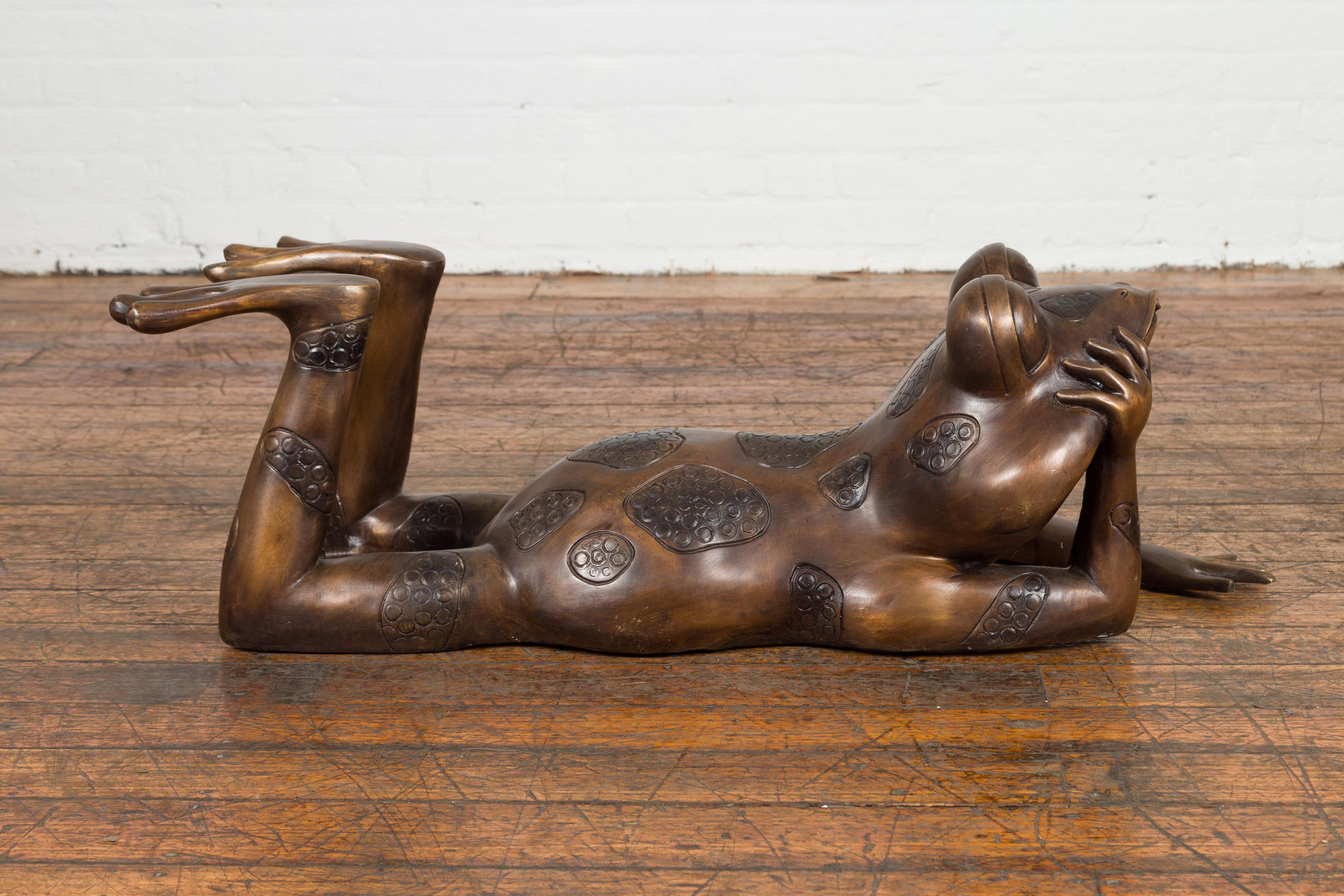 Daydreaming Frog, a lost wax cast bronze sculpture depicting a frog laying on its belly, tubed as a fountain. Presenting the 