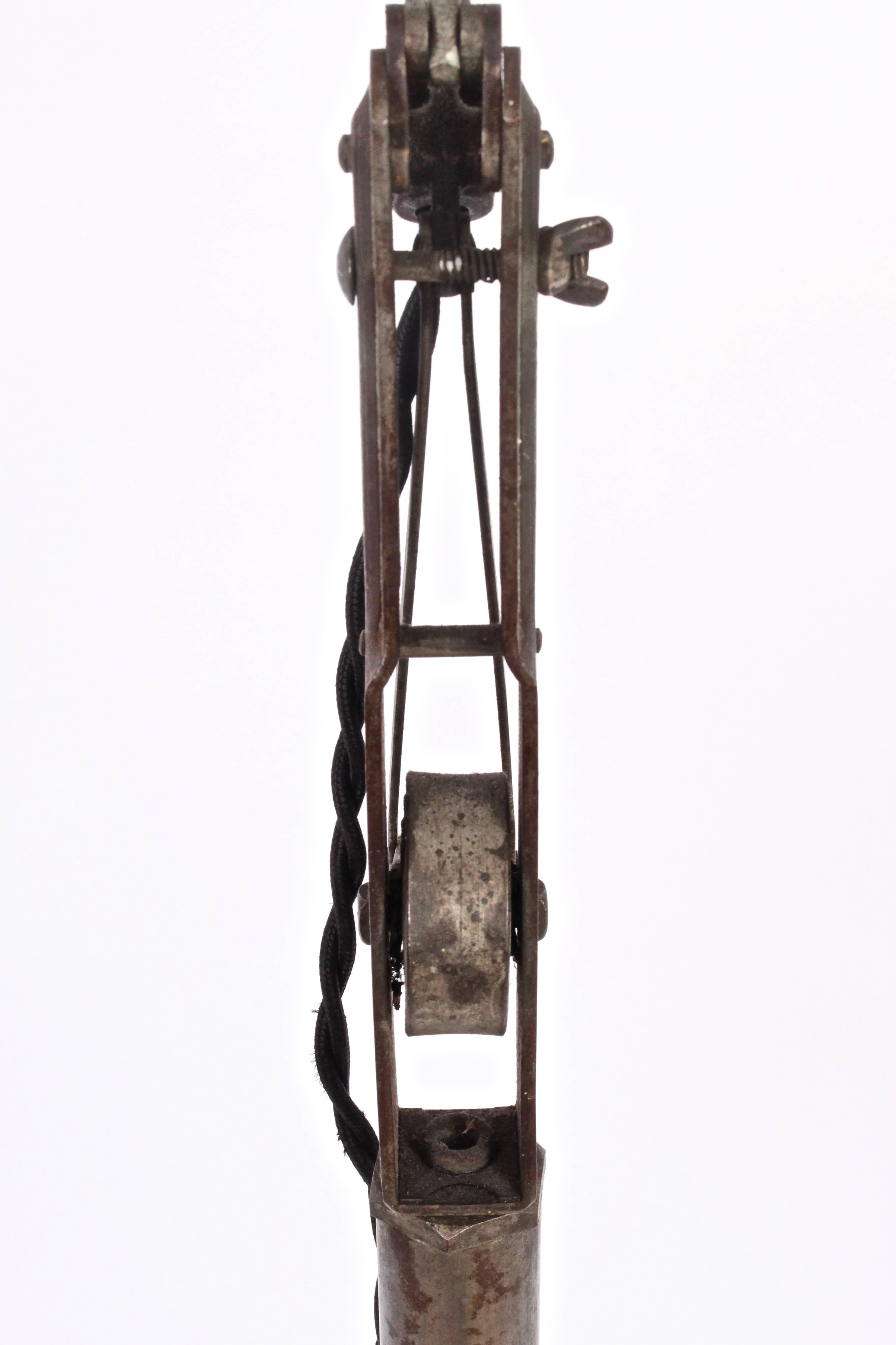 Early 20th century industrial adjustable Dazor iron floor reading work light. Featuring articulated spring loaded arms, dark green enameled tin shade, iron pipe centre column and on a heavy round 12