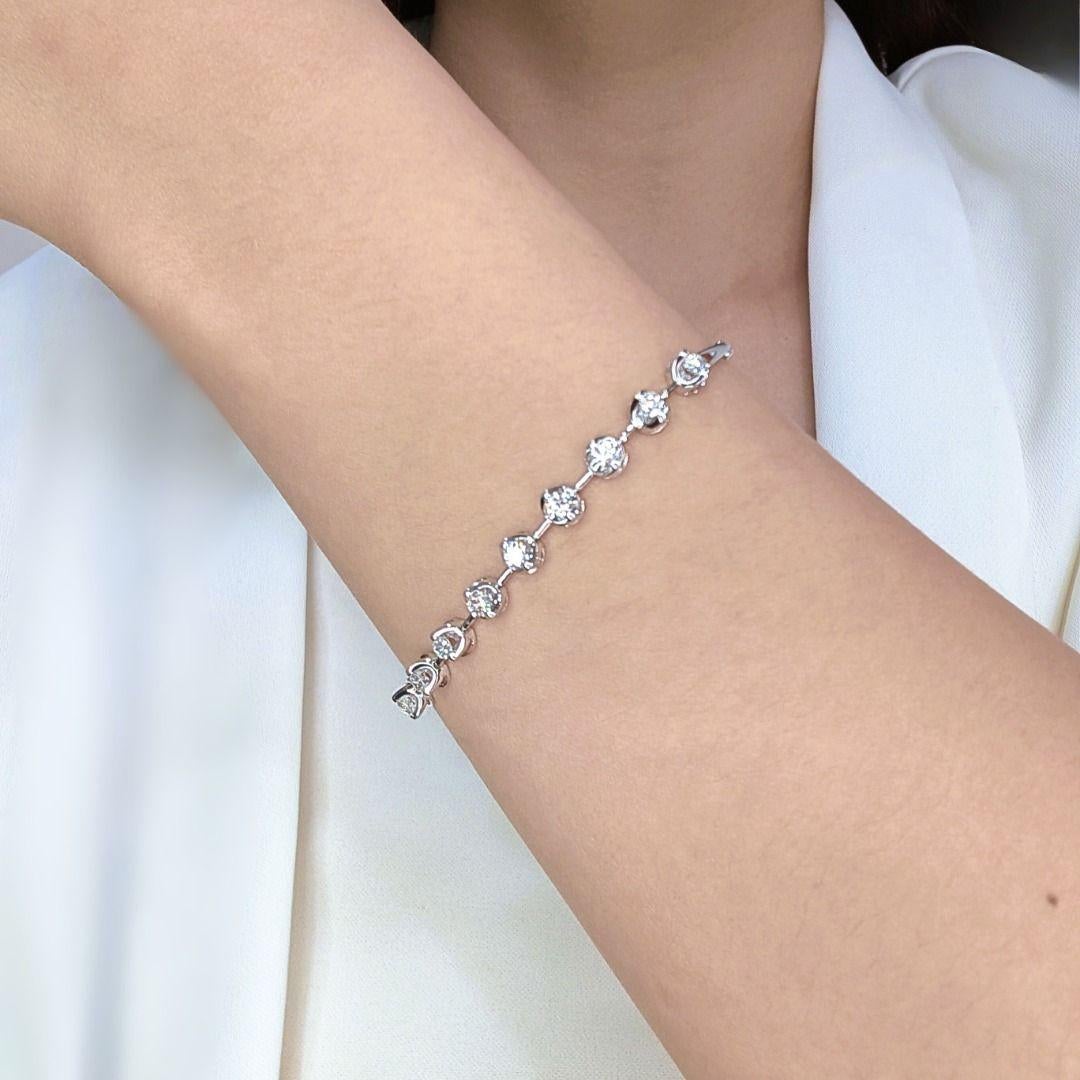 Adorn your wrist with understated elegance wearing this beautiful diamond bracelet, meticulously crafted in sleek 18K white gold. The refined design features nine scintillating natural round brilliant diamonds, thoughtfully set along the bracelet to