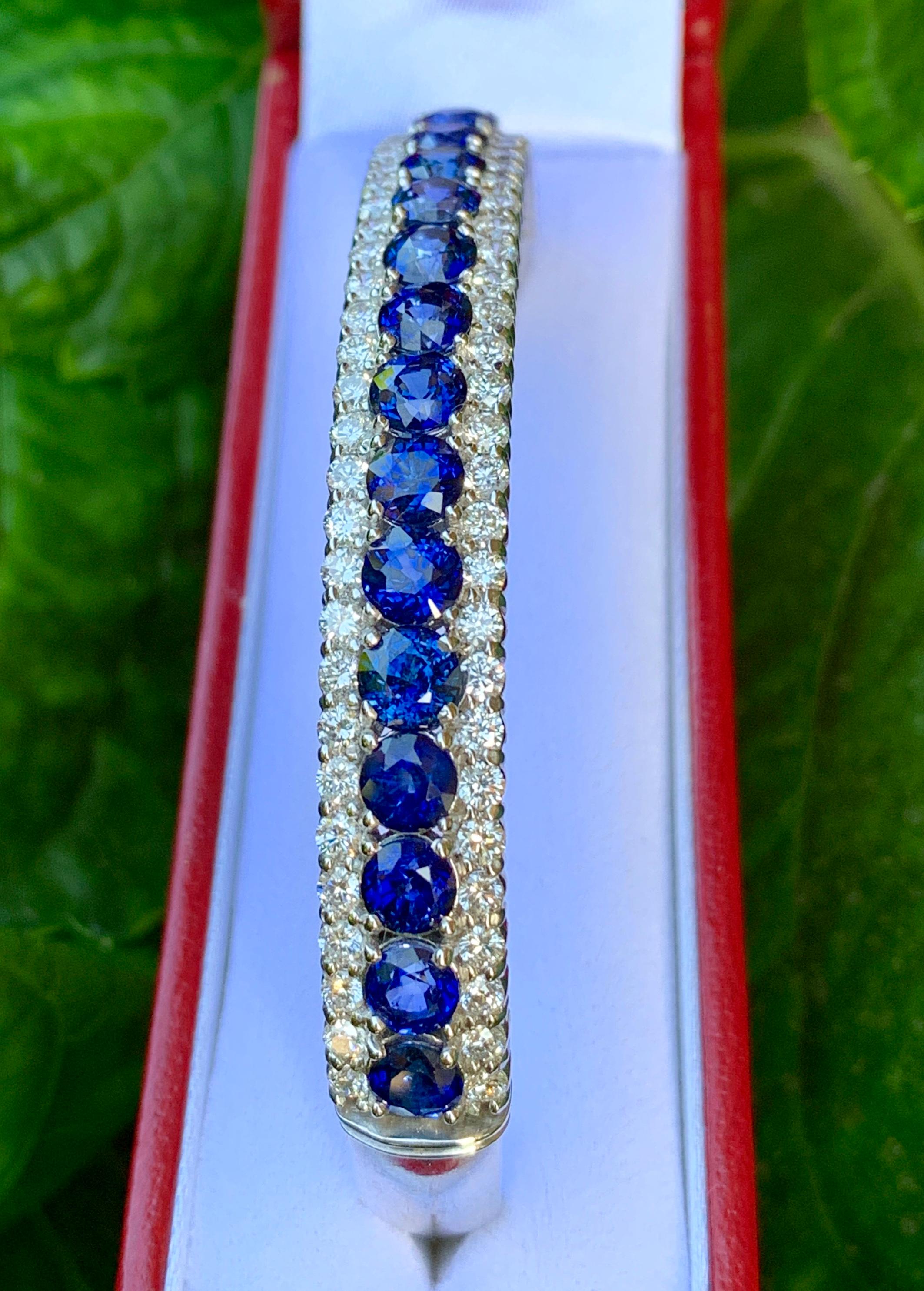Sparkling sapphire and diamond 18 karat white gold estate hinged bangle bracelet features a row of prong set round blue sapphires centered between two rows of prong set round brilliant diamonds.

18 sapphires graduate in size from 4.4 mm to 4.9 mm