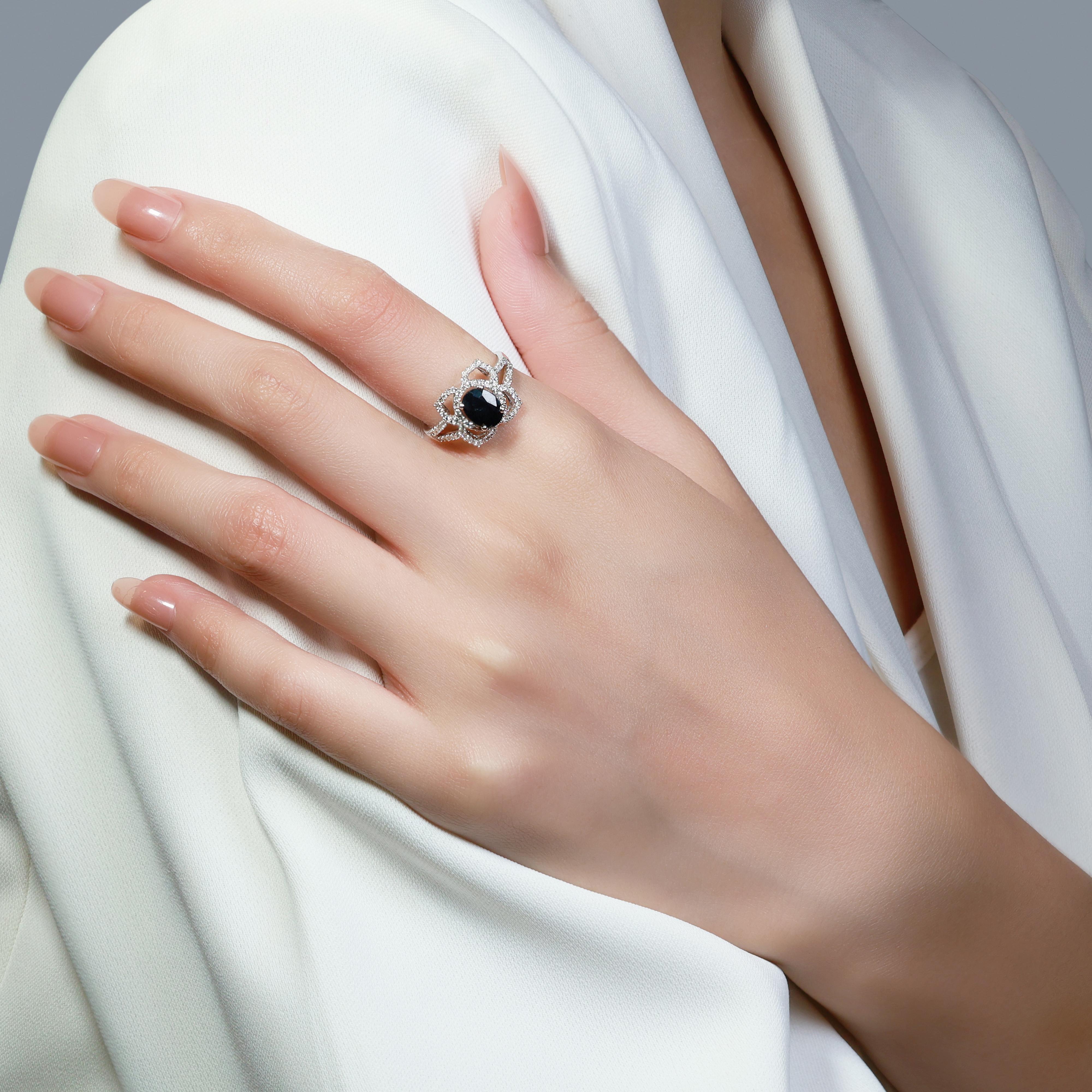 This captivating piece of jewelry is expertly crafted from 18K white gold, exuding a sense of modern elegance and luxury. At its center lies a stunning oval sapphire, weighing 1.45 carats and showcasing a rich blue hue that adds a vibrant pop of
