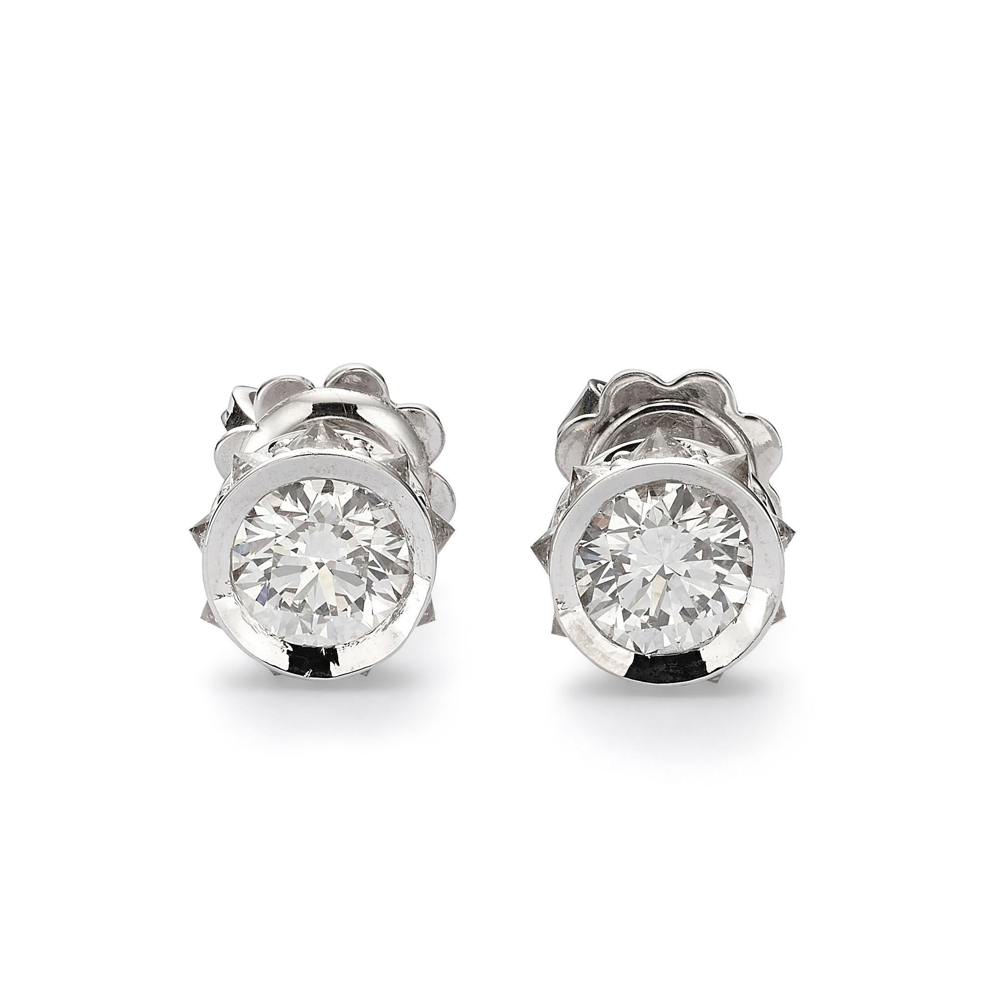 These stunning earrings exemplify a captivating design that flawlessly combines elegance and craftsmanship. Expertly crafted from 18K white gold, they showcase two exquisite GIA-certified round diamonds, each boasting a G color grade and SI1