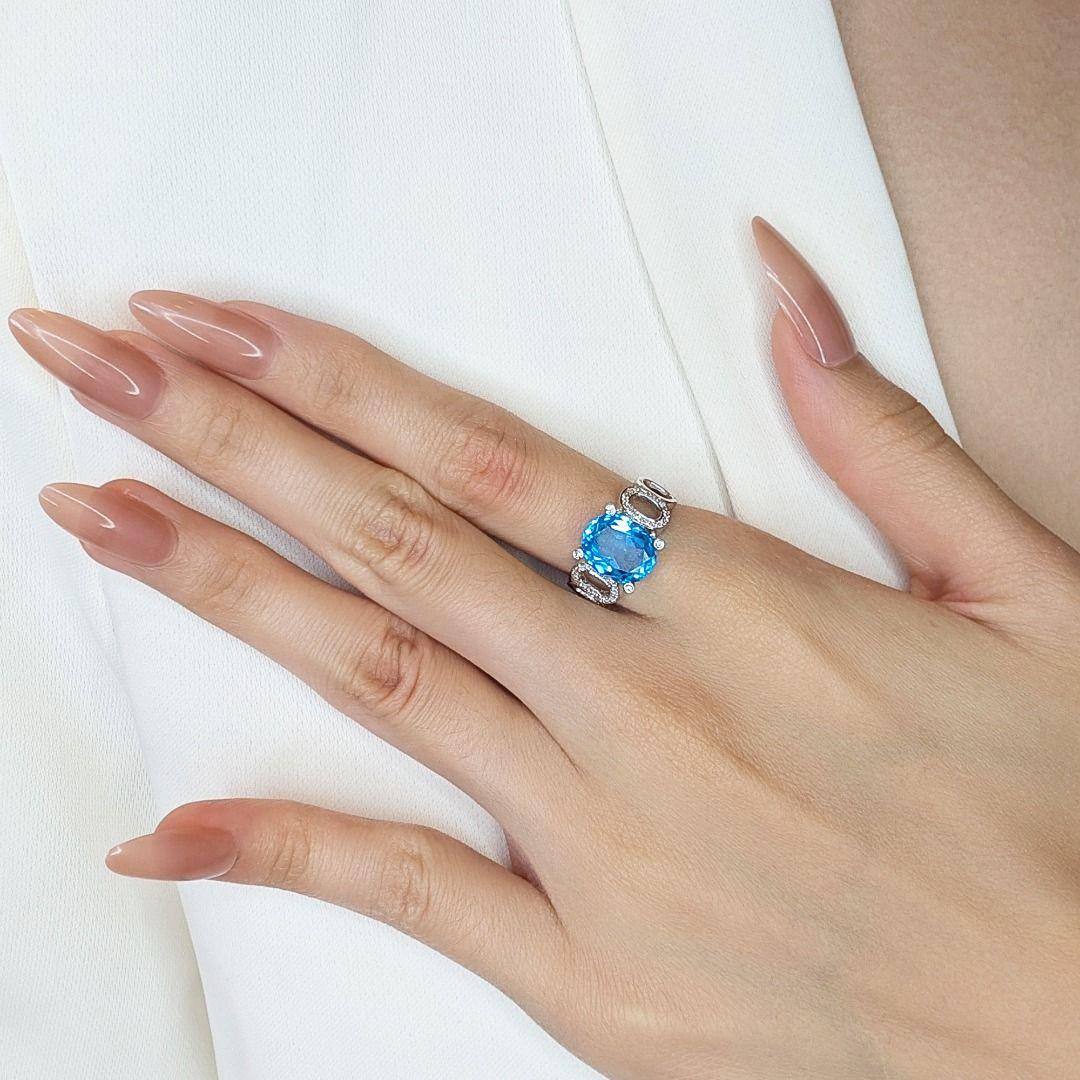 This exquisite ring, crafted from 18K white gold, features a stunning 2.18ct oval-shaped light-blue topaz as its centerpiece, radiating elegance and charm. Accentuated by 36 natural round brilliant diamonds (0.18ct, G color, VS clarity), the ring