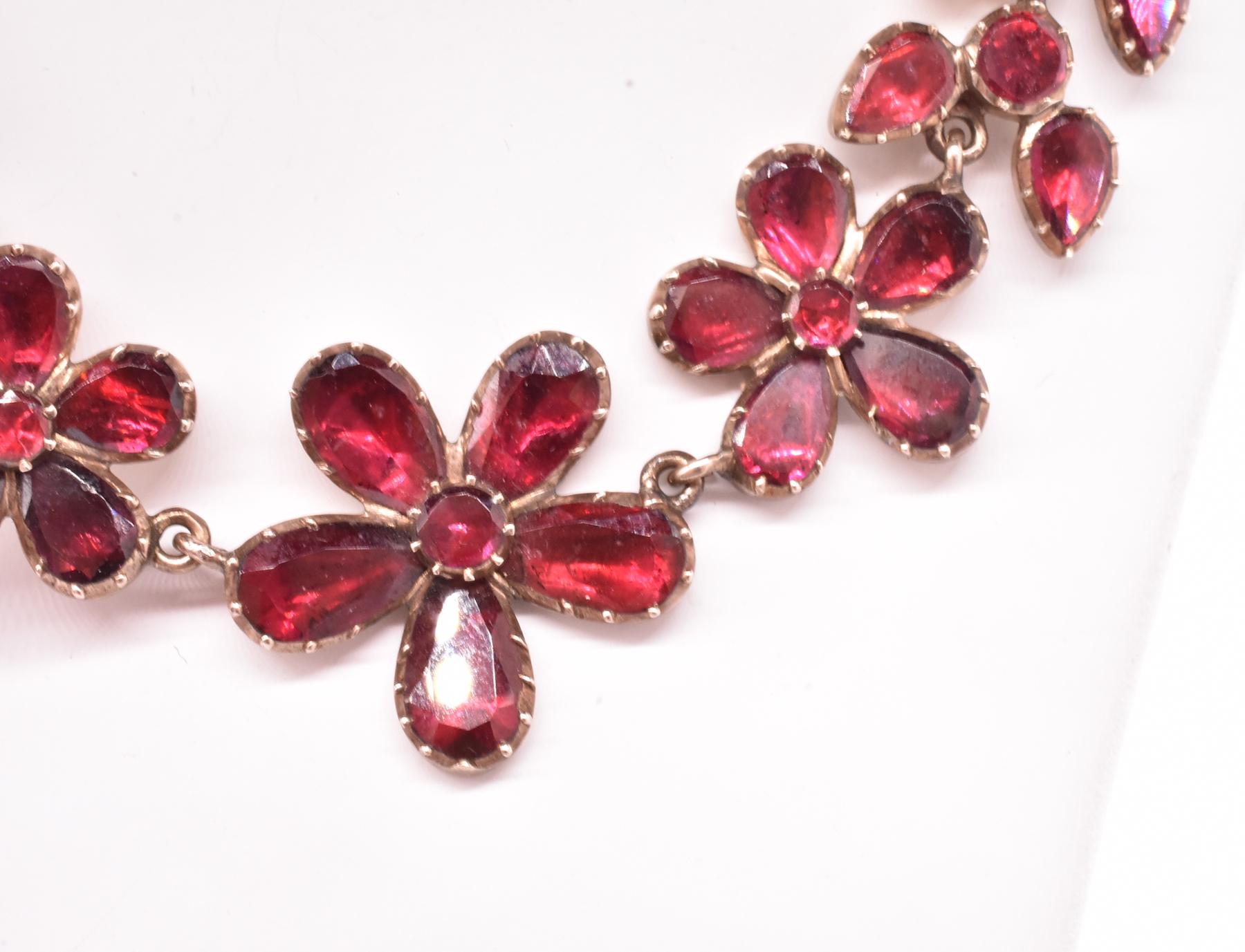Flat cut almandine garnets were the most popular gemstone of the Georgian period shown here in a rarely found naturalistic floral and leaf design necklace set in 18K gold. The pansy shaped flowers represent remembrance and are graduated in size.