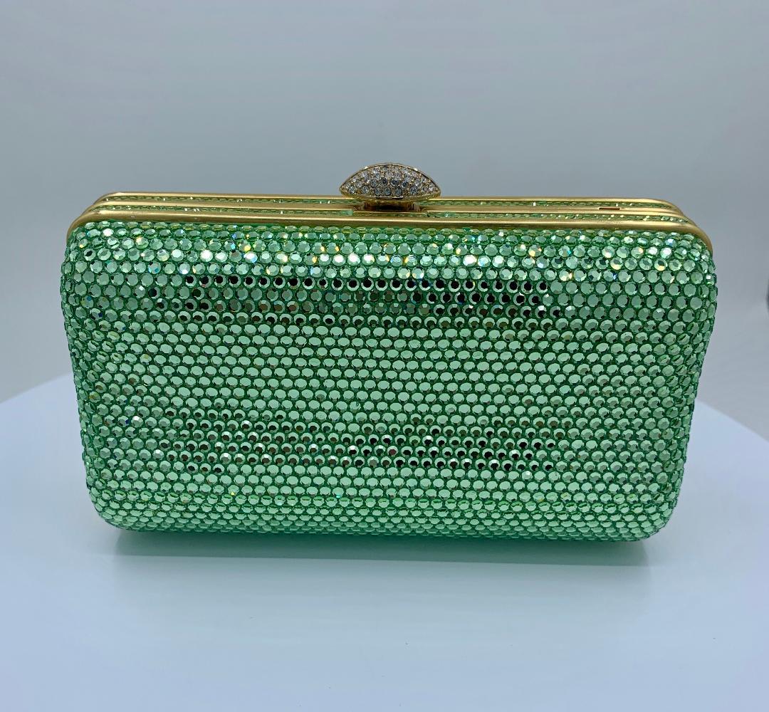 Dazzling handmade couture designer, Judith Leiber, crystal minaudiere evening bag or evening clutch is completely covered in green crystals. Gold toned metal frame with metallic gold leather lined interior and a long gold shoulder chain is tucked