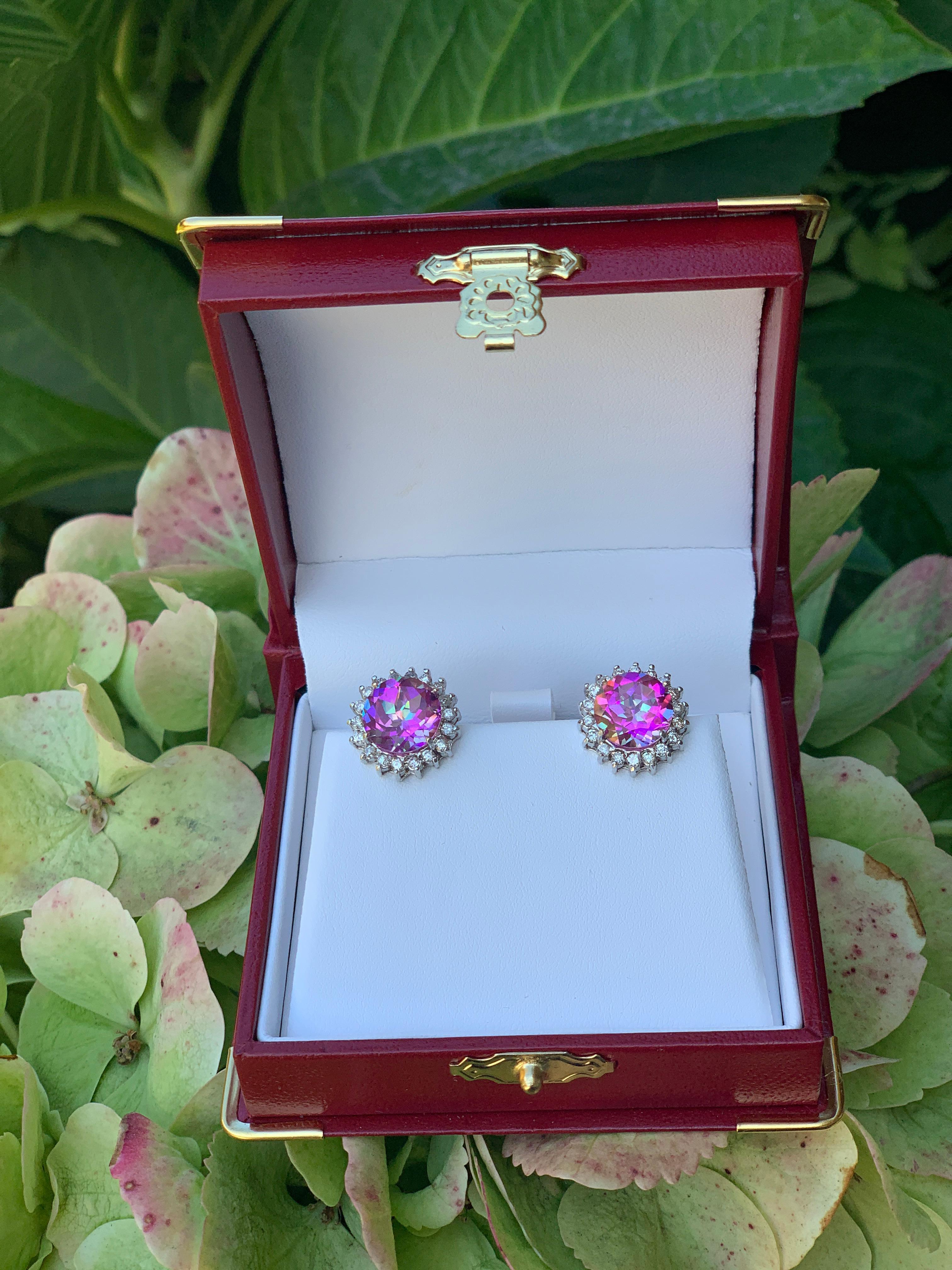 Fabulous bright pink mystic topazes are round brilliant cut and reflect sparks as if lit from within.  The topazes are prong set in 14 karat white gold and surrounded by a sparkling halo of prong set round brilliant diamonds to create a dazzling