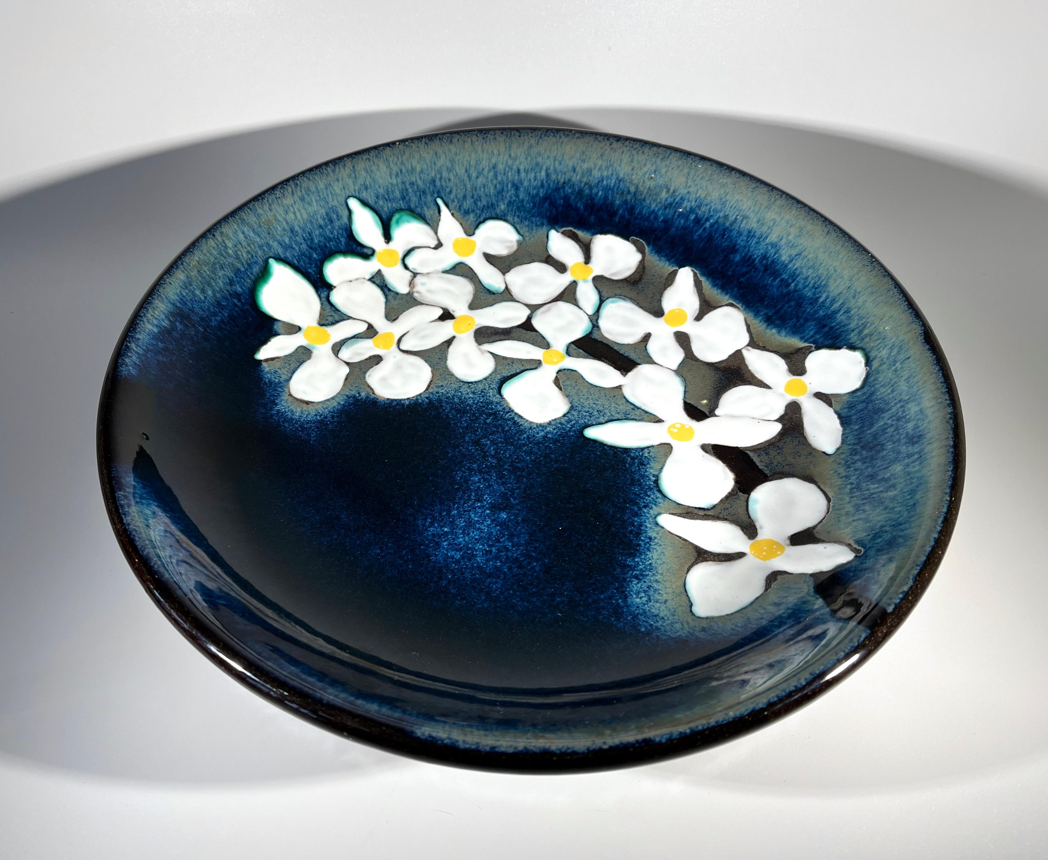 Effortless white orchids on an intense dark blue glazed ground, decorate this large shallow bowl 
A beautiful and functional piece by Upsala Ekeby of Sweden
Dark brown glaze on reverse
Circa 1960
Signed Ekeby to base
Height 2 inch, Diameter 11
