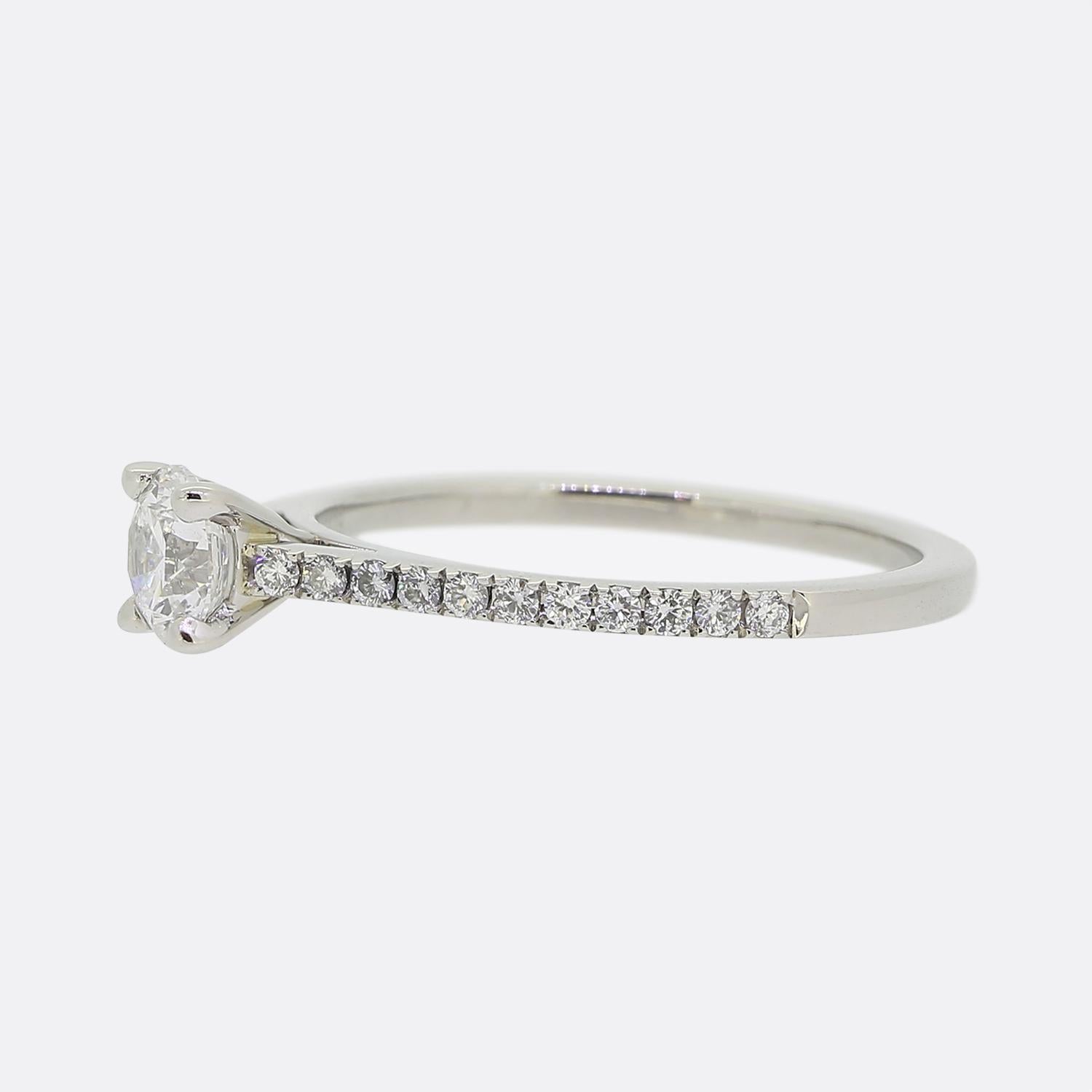 Here we have a classic platinum diamond solitaire ring from the world renowned diamond group, De Beers. This ring showcases a central round brilliant cut diamond with 11 round matching smaller stones at each shoulder.

A perfect engagement ring,