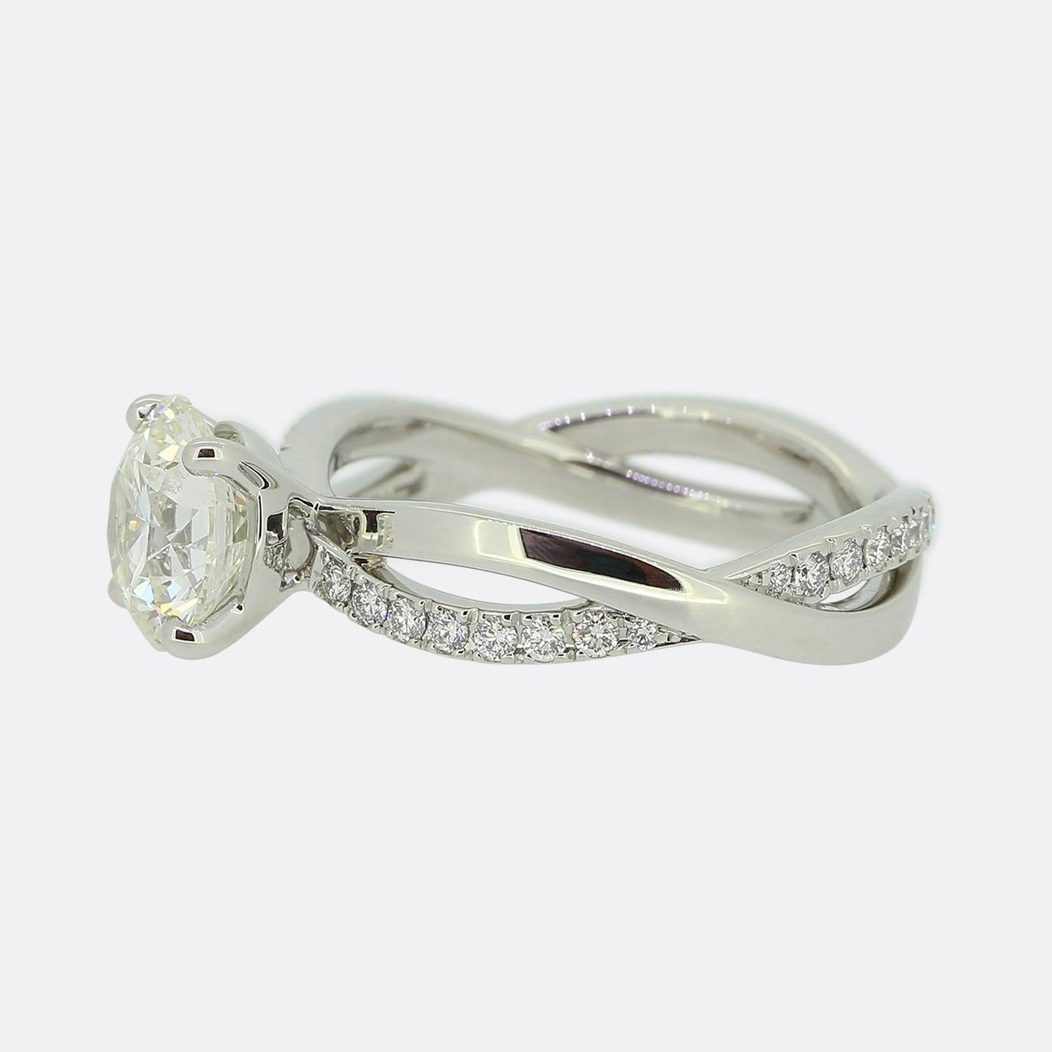 Here we have an excellently crafted ring from the world renowned diamond group, De Beers. At the centre of the face, a round brilliant cut diamond draws the eye and is harmoniously accentuated by a double banded back drop which swirls around the