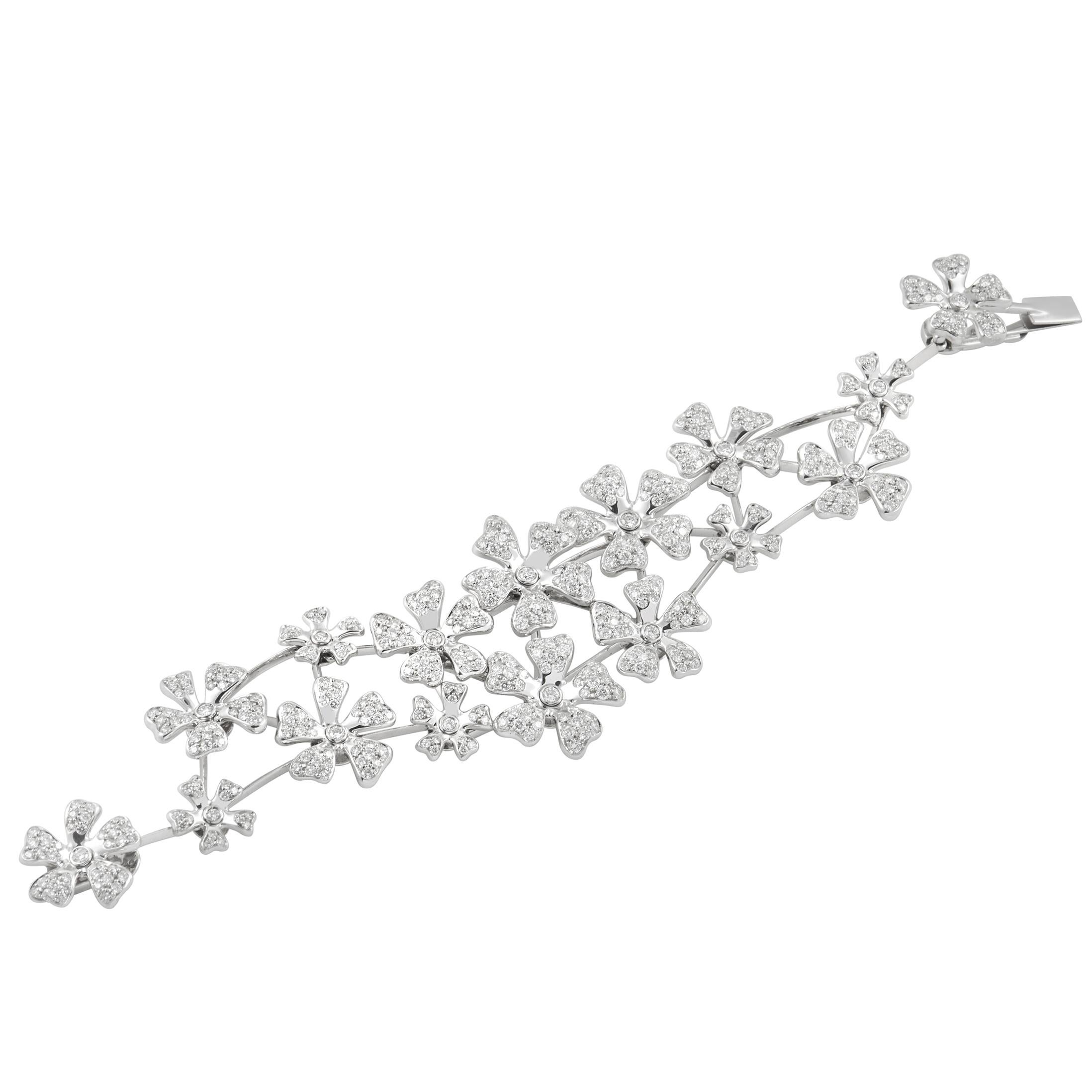 This De Beers bracelet is a stunning accessory. The bracelet is crafted from 18K white gold, and wraps around the wrist with a linked flower pattern. The bracelet is set with 7.00 carats of sparkling round diamonds throughout, and has a total length