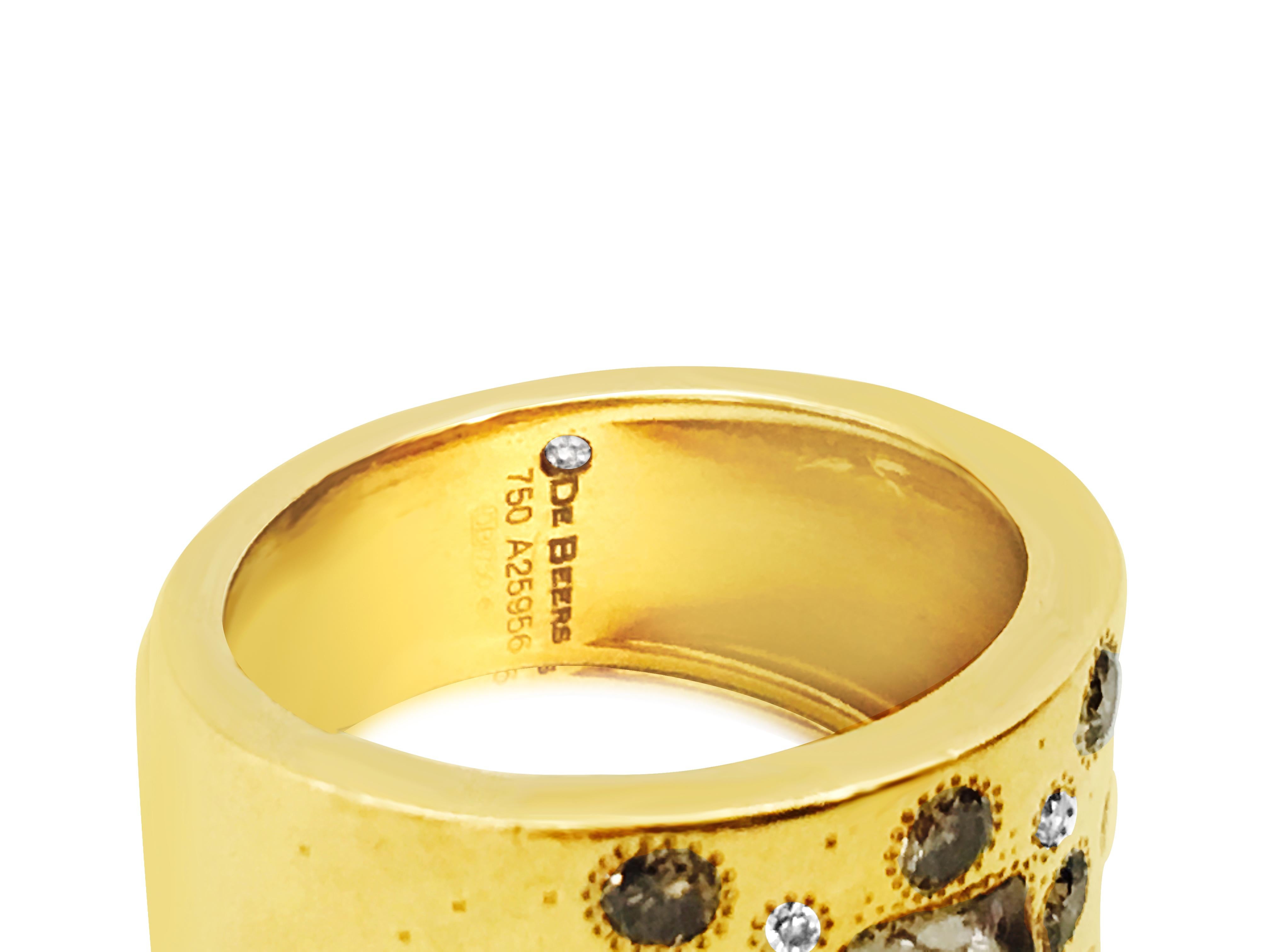 Forged from 18K yellow gold, this De Beers talisman collection ring boasts a rough diamond center accompanied by round brilliant cut side diamonds and fancy color diamonds, all sourced from natural earth mines. With its signature design and
