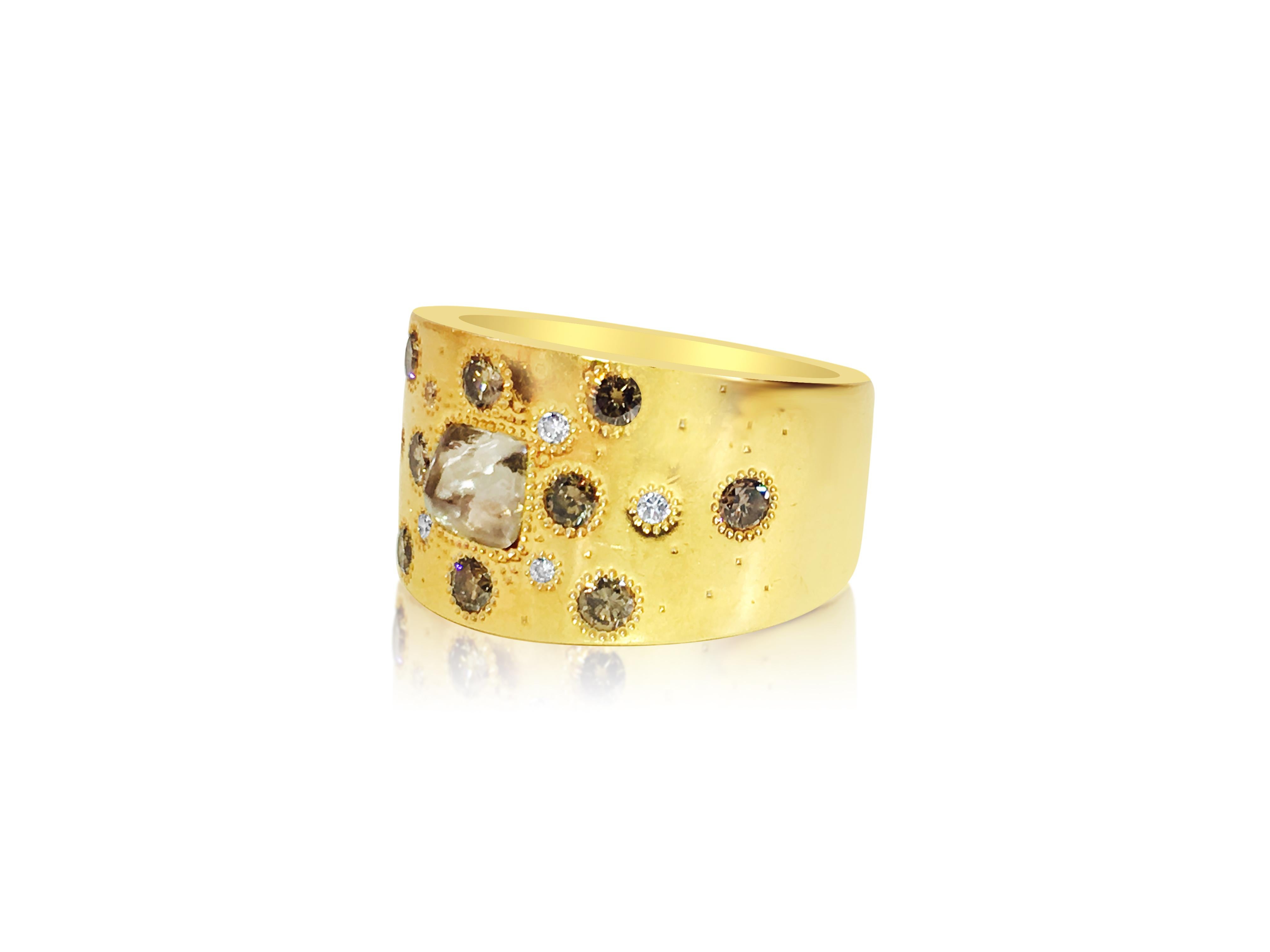 Forged from 18K yellow gold, this De Beers talisman collection ring boasts a rough diamond center accompanied by round brilliant cut side diamonds and fancy color diamonds, all sourced from natural earth mines. With its signature design and