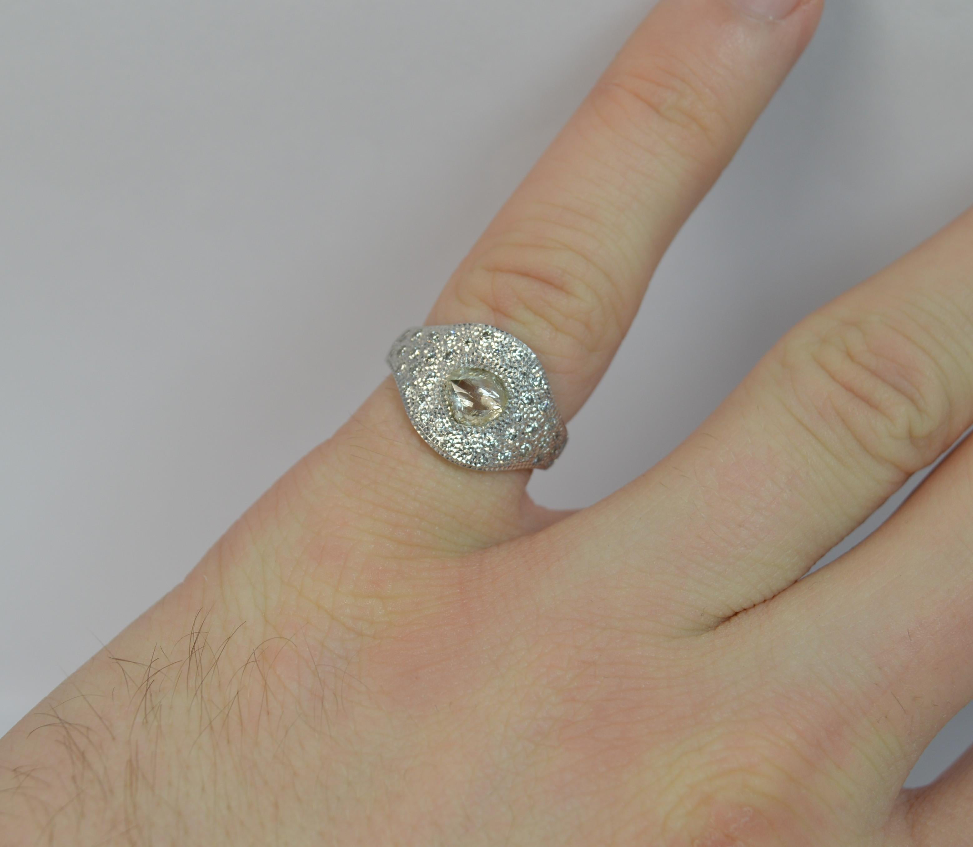 A stunning and highly unusual De Beers designer ring. Known as a Talisman ring.
SIZE ; H 1/2 UK, 4 US
Modelled in 18 carat white gold throughout.

To the centre is a rough un cut diamond, 5.3mm x 5.8mm approx.

Surrounding are modern round brilliant