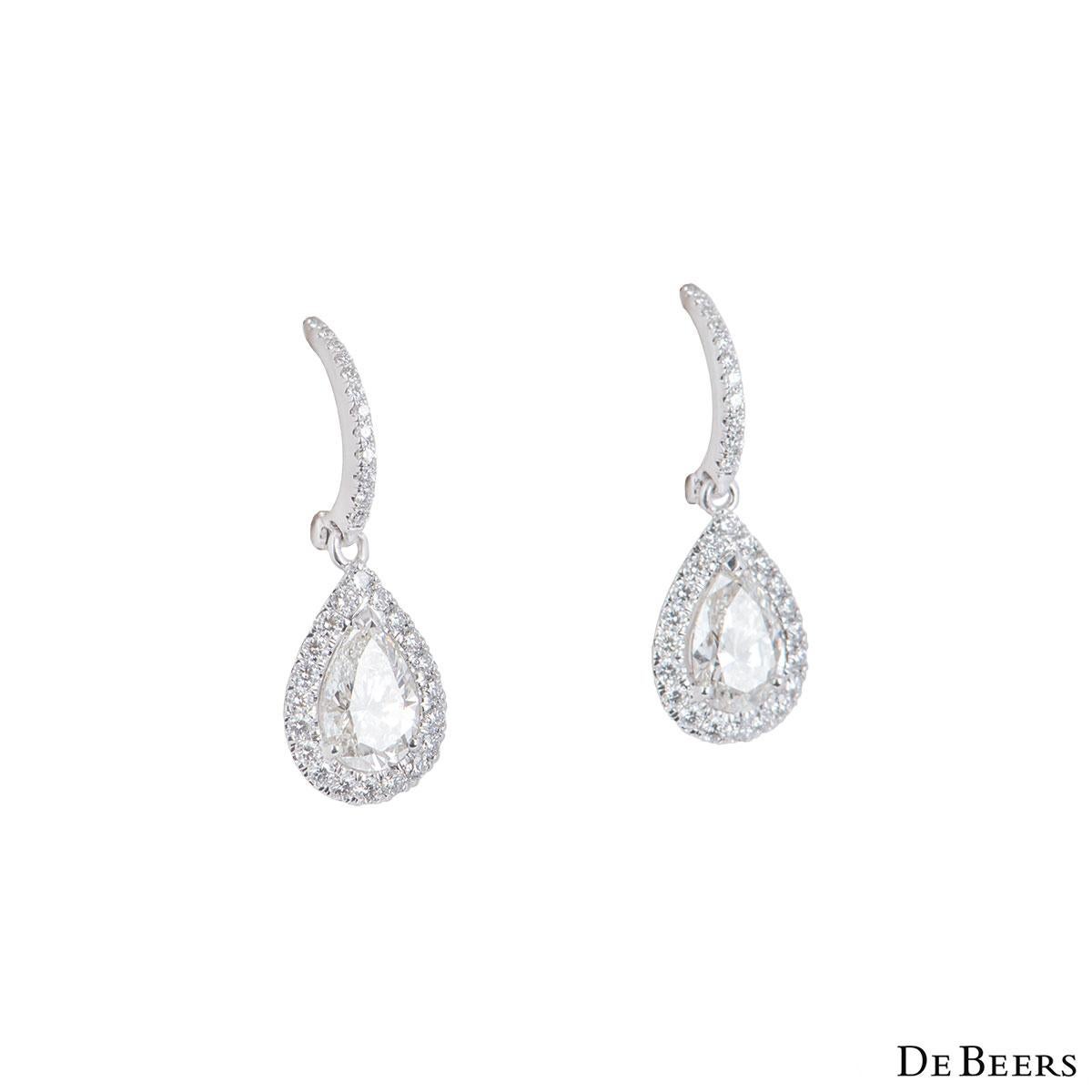 A beautiful pair of 18k white gold DeBeers diamond earrings from the Aura collection. The earrings feature a pear cut diamond in a prong setting and pave set diamonds around it and on the stem. The pear cut diamonds have a total weight of 1.42ct, H