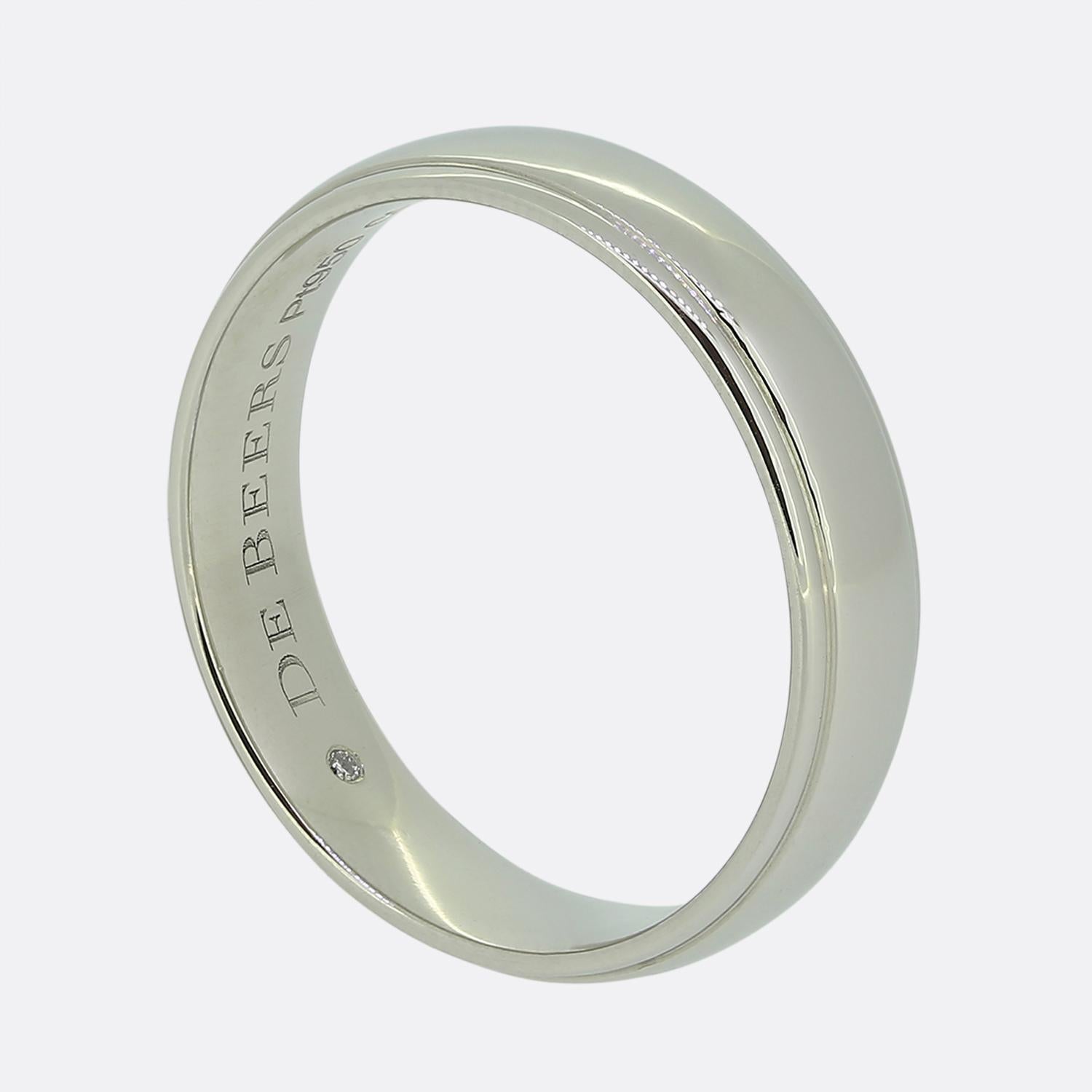 Here we have a sleek band ring crafted from platinum by De Beers. The design is minimalist, featuring a smooth, polished surface that reflects light elegantly. The interior of the band is engraved with the brand name, adding a subtle touch of