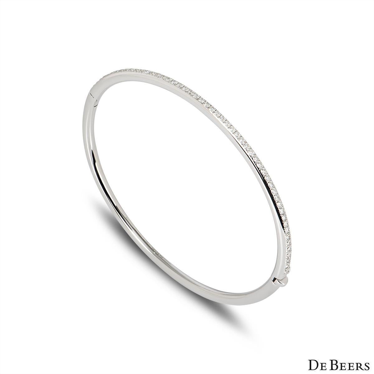 A timeless 18K white gold classic diamond bangle by De Beers. This bangle features 52 micropavé set round brilliant cut diamonds totalling 0.64ct, predominately F-G colour and VS clarity. The bangle fits a wrist size of up to 16cm, finishes with a