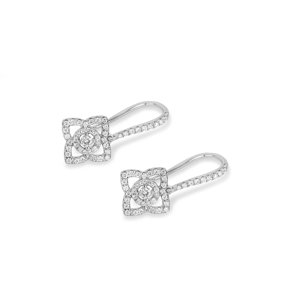 A sparkly pair of 18k white gold diamond earrings by De Beers from the Enchanted Lotus collection. The drop earrings feature a freely moving openwork lotus motif set below a micropave row of diamonds. The 94 round brilliant cut diamonds pave set
