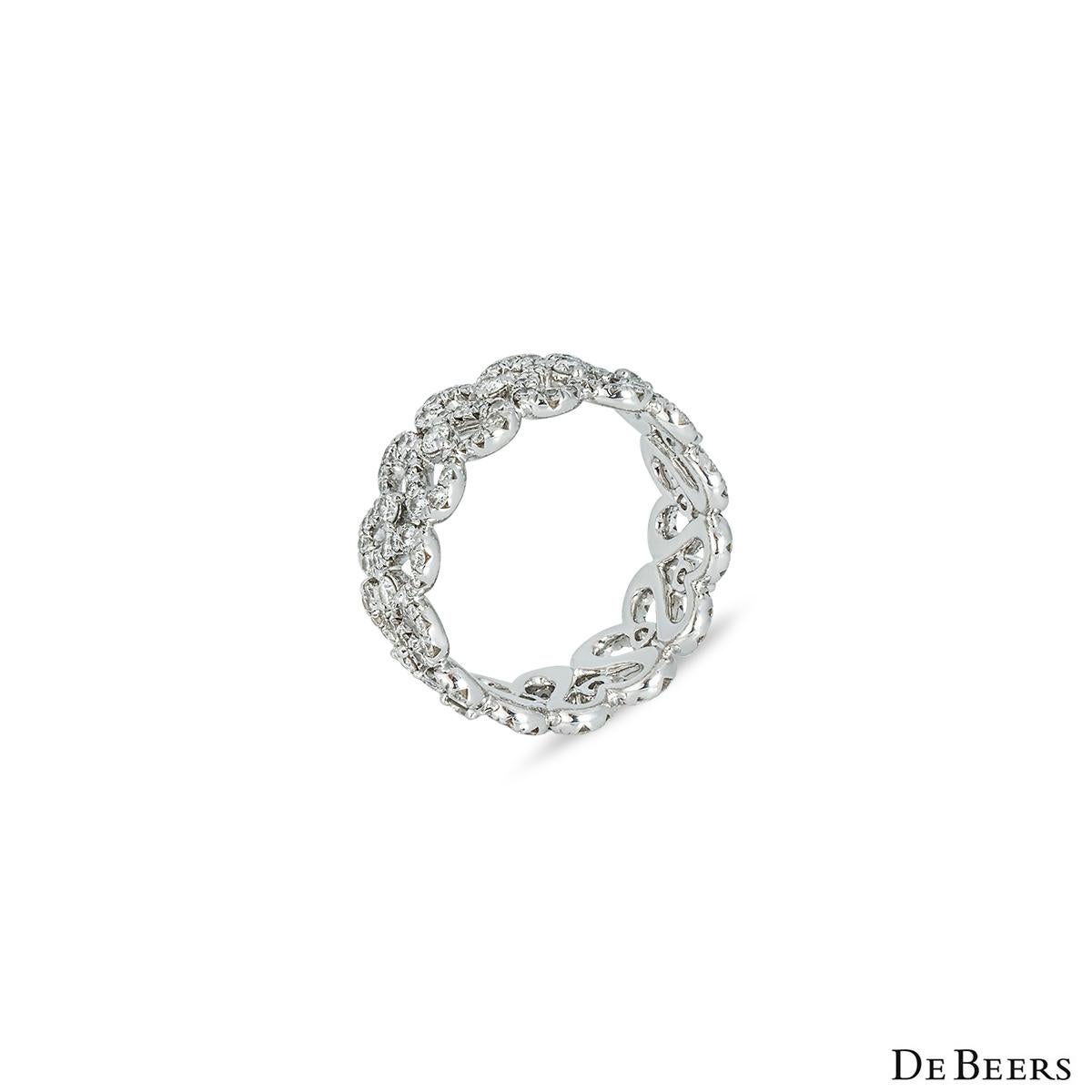 An elegant 18k white gold diamond ring by De Beers from the Classics collection. The band is set with 7 openwork motifs portraying two swans entwined together, set with micro-pave diamonds. Where each motif meets there is a single round brilliant