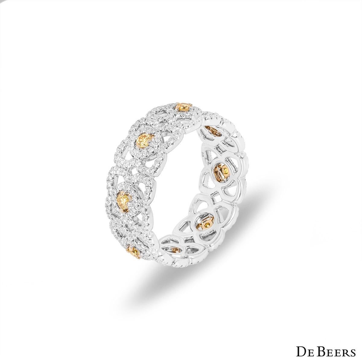 A mesmerizing 18k white gold diamond ring by De Beers from the Enchanted Lotus collection. The band is set with 8 lotus motifs set to the centre with a round brilliant cut yellow diamond with an approximate total weight of 0.40ct. Complementing the