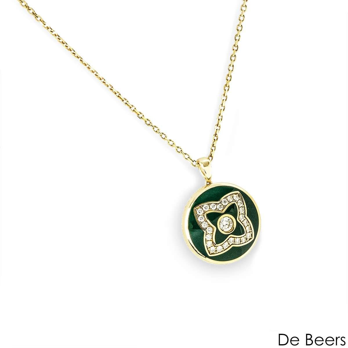 Una bellissima collana in oro giallo 18k di De Beers, della collezione Enchanted Lotus. Il pezzo presenta un pendente con motivo a loto ornato di smalto verde e incastonato con 25 diamanti rotondi a taglio brillante, più un ulteriore diamante sul