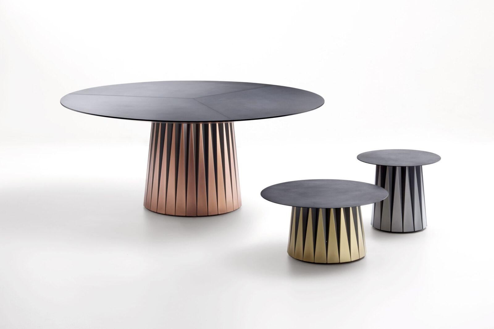 Inspired by the art of origami, the Coste table collection is an ode to the technique of folding metal. The conical trunk at the centre is composed of the juxtaposition inherent to a folded module, whose 'ribbing’ generates a series of isosceles