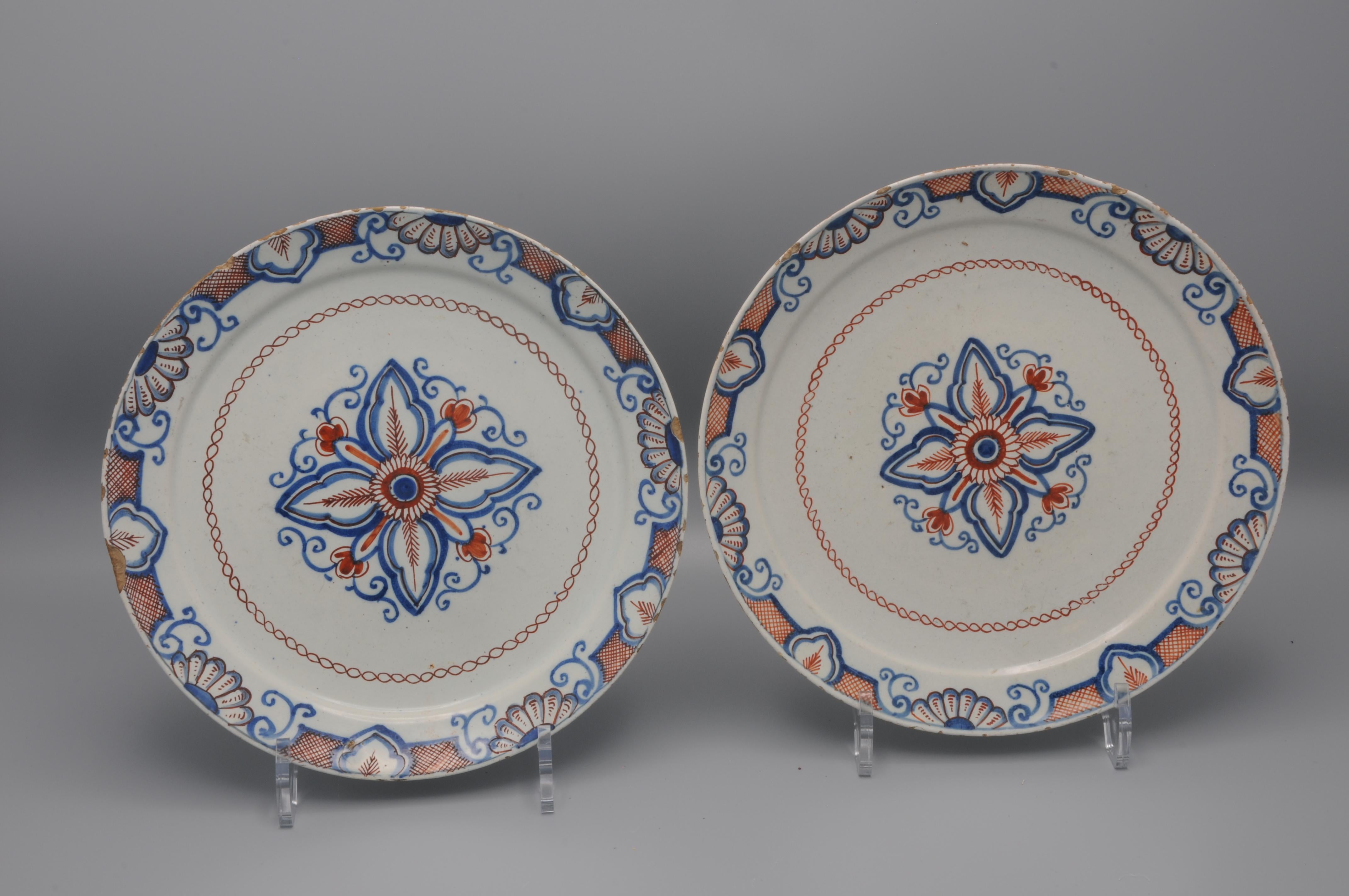 Excellent pair of mid 18th century Delftware plates with a rare geometrical decoration of a stylized flower with foliate scrolls. 
Border adorned with foliage scrolls and shells in Daniel Marot style. 

Marked IVL for Johannes and Margaretha van