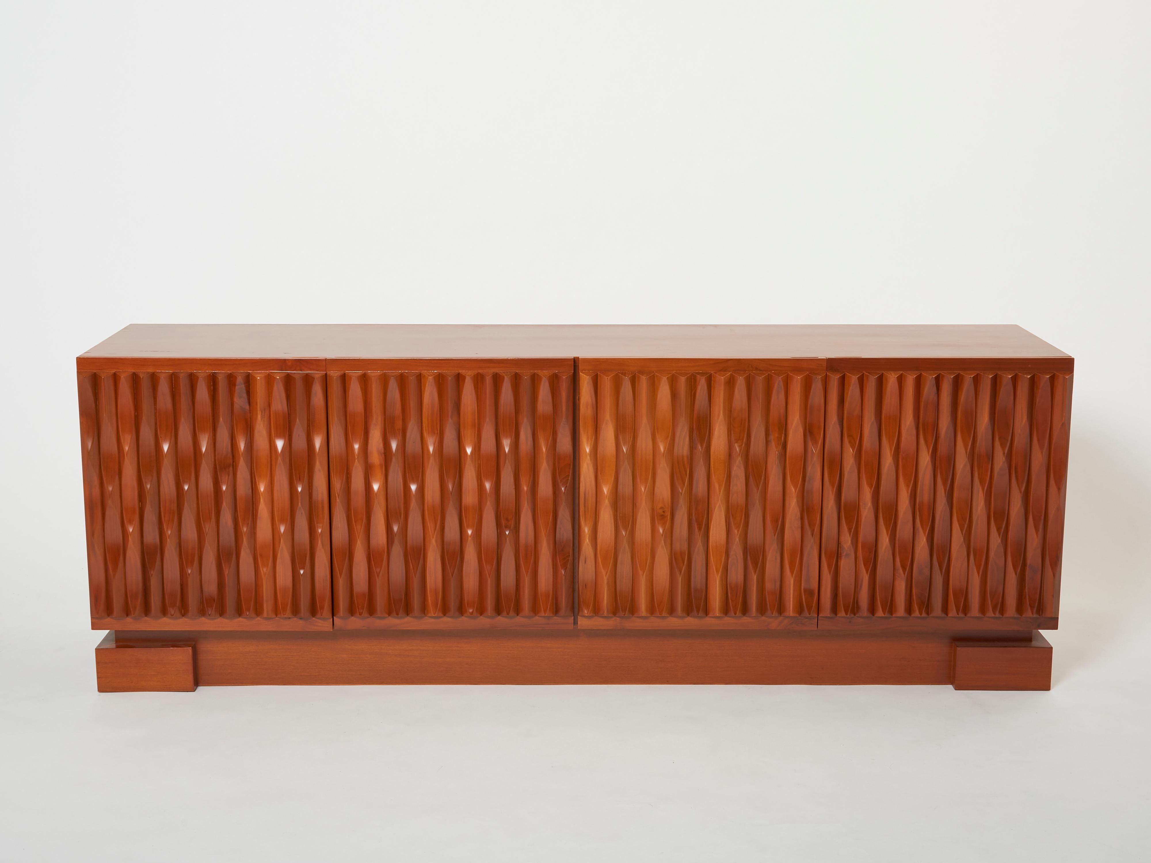 A unique and timeless vintage piece, this mid-century sideboard feels imposing and architectural, with straight lines and geometric patterns. Made from solid Mahogany by De Coene in Belgium in the late 1970s, it features four graphic carved doors