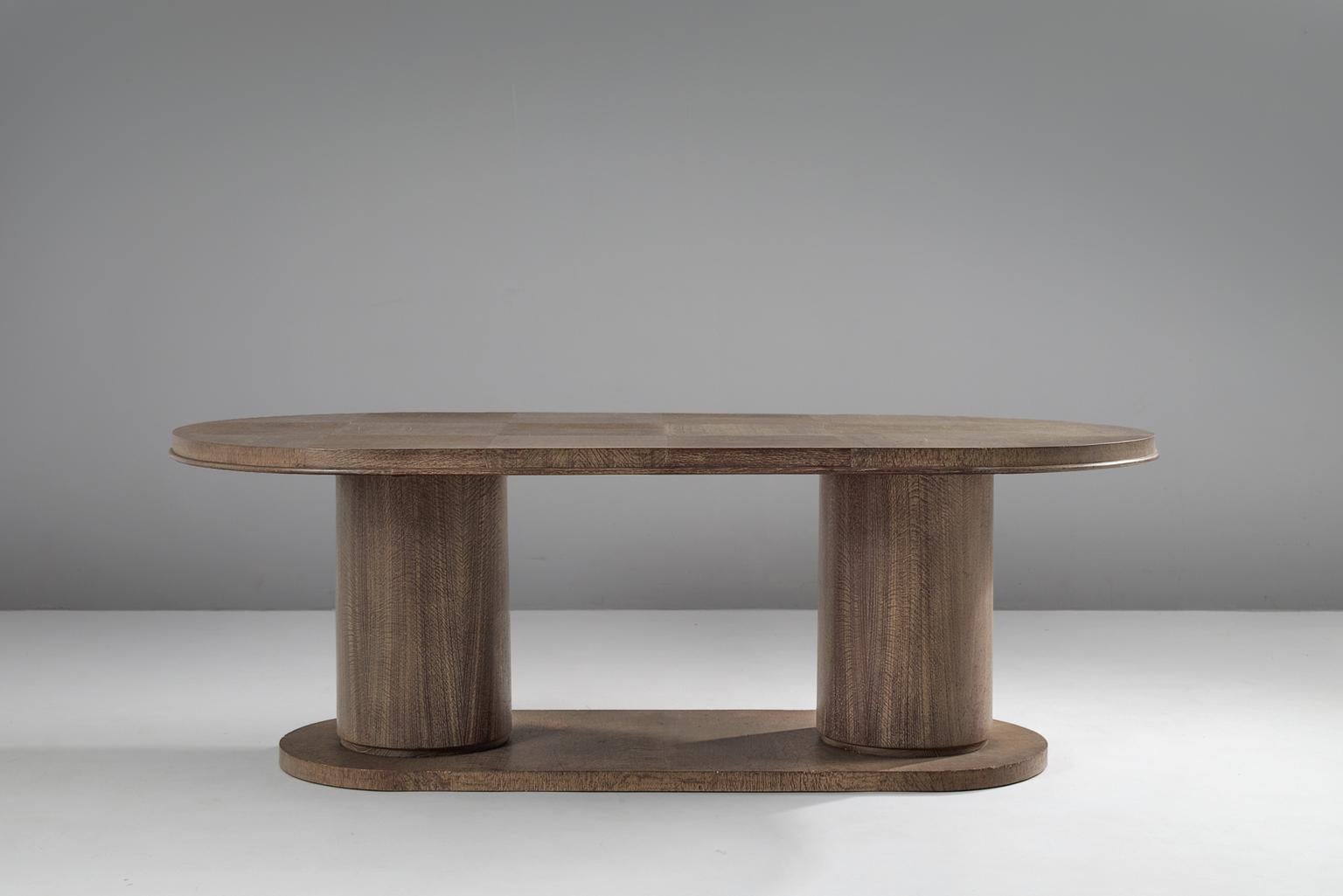 Dining table, in cerused oak, by De Coene, Belgium, 1930s. 

Imposing large oval center table. This table has a strong and sturdy appearance, due the two column base. While the design looks simplistic, the top is highly detailed. The oval shaped