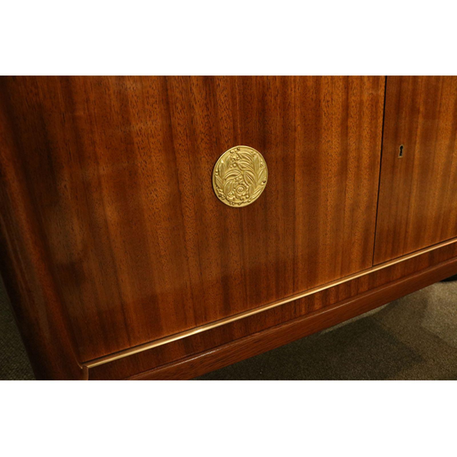 A Belgian Art Deco period bar cabinet designed by De Coene Frères from Brussels, Belgium circa 1930. Wood veneer with a distinctive grain pattern with two decorative patinated bronze medallions on the pair of cabinet doors as well as bronze sabots.