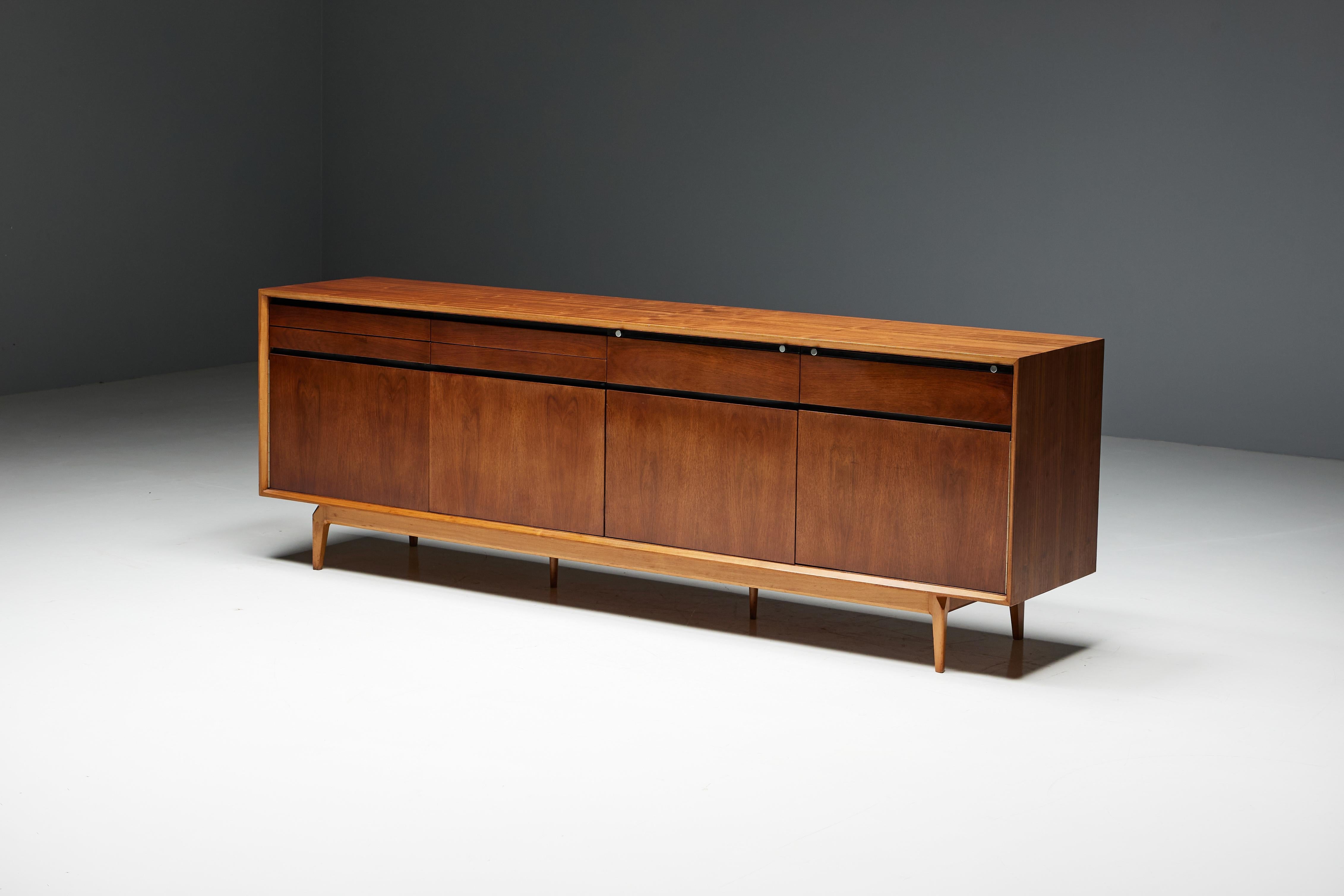 Conçu par De Coene en 1958, ce buffet Madison est méticuleusement fabriqué à partir de bois de rose et de noyer. Cette pièce exquise présente des lignes bien définies et des détails intrigants, tels que les portes pliantes distinctives. Les poignées