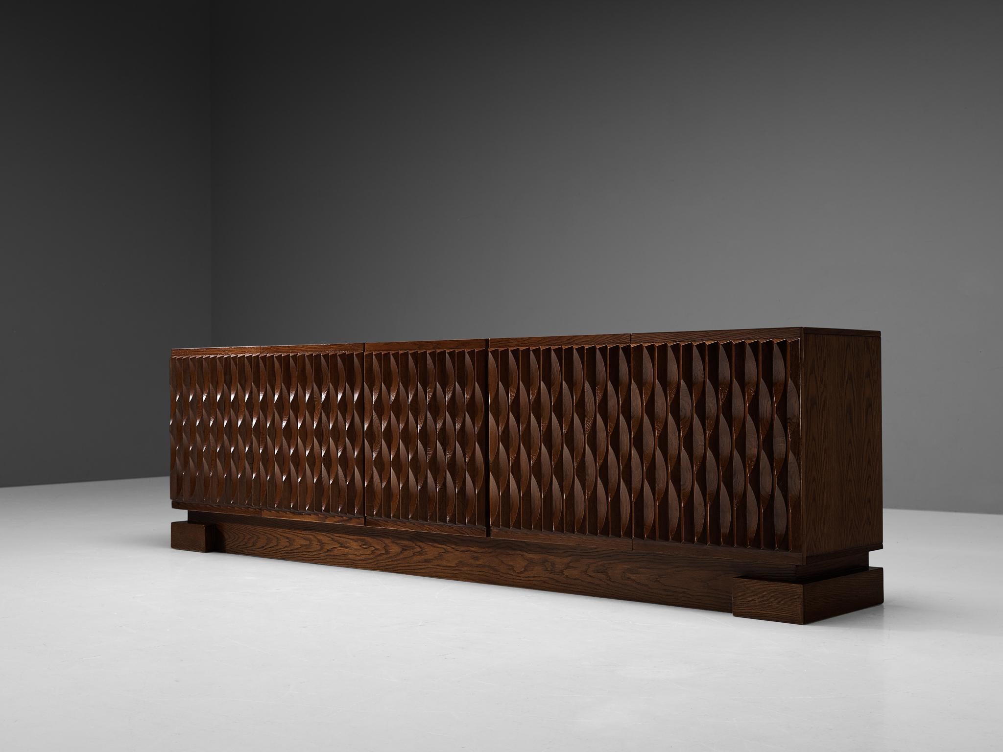 De Coene, sideboard, stained oak, Belgium, 1970s.

This sideboard with geometric doors is manufactured by De Coene. The cabinet shows an intriguing graphic pattern on its doors. The five beautifully carved doors provide access to the storage space