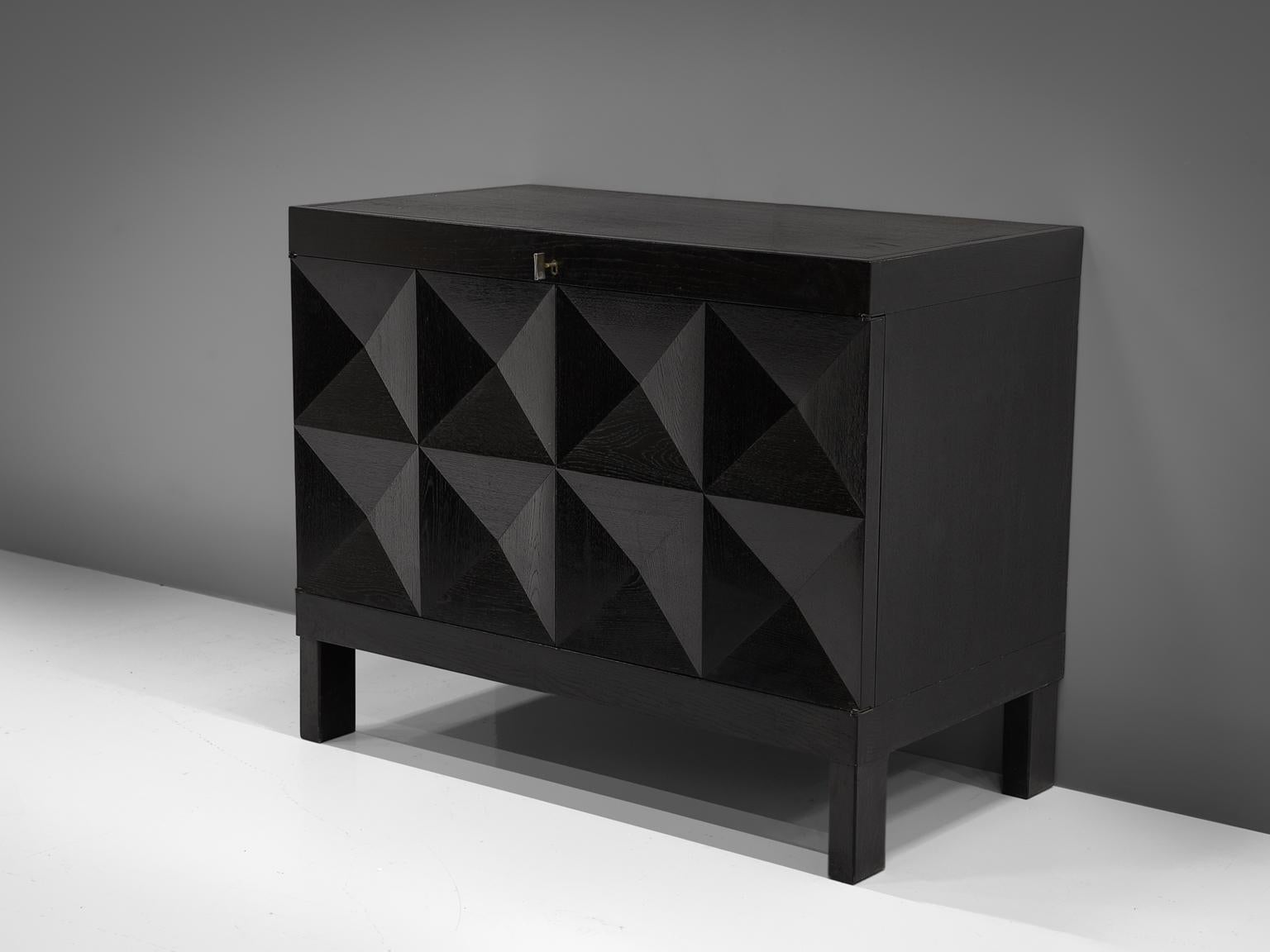 De Coene, cabinet in stained oak, Belgium, 1970s. 

This small sideboard with geometric doors is executed by De Coene. The credenza shows a pyramid like pattern on its doors. The squares on the front are each divided in four quarters and the chest