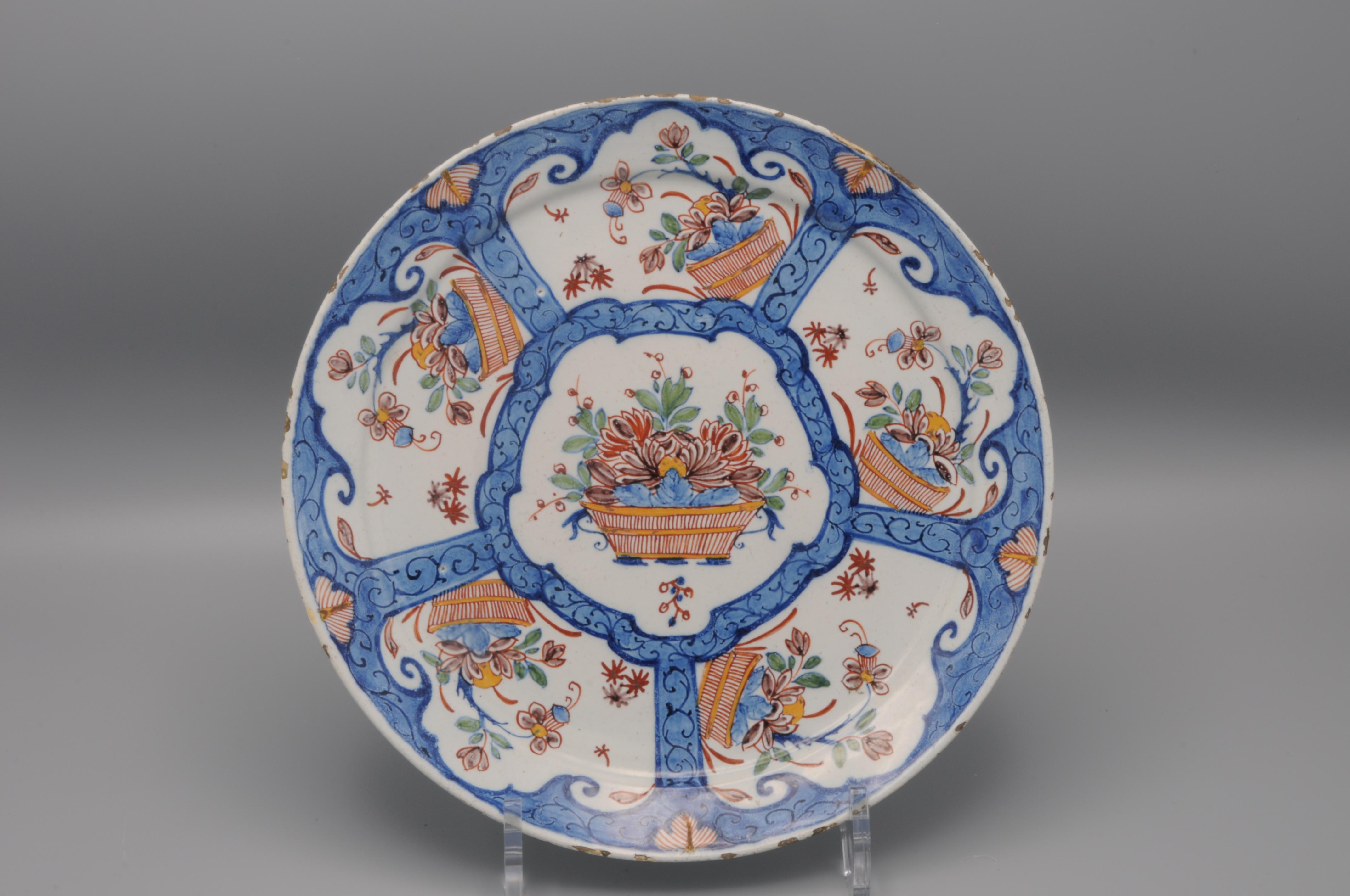 Mid 18th century Blue Delftware plate with central decoration of a flower baskets, surrounded by 5 cartouches with similar decoration. 
Marked 'D' for  Jan Teunis Dextra, owner of De Grieksche A, 1757-1765
Excellent quality of painting
Good