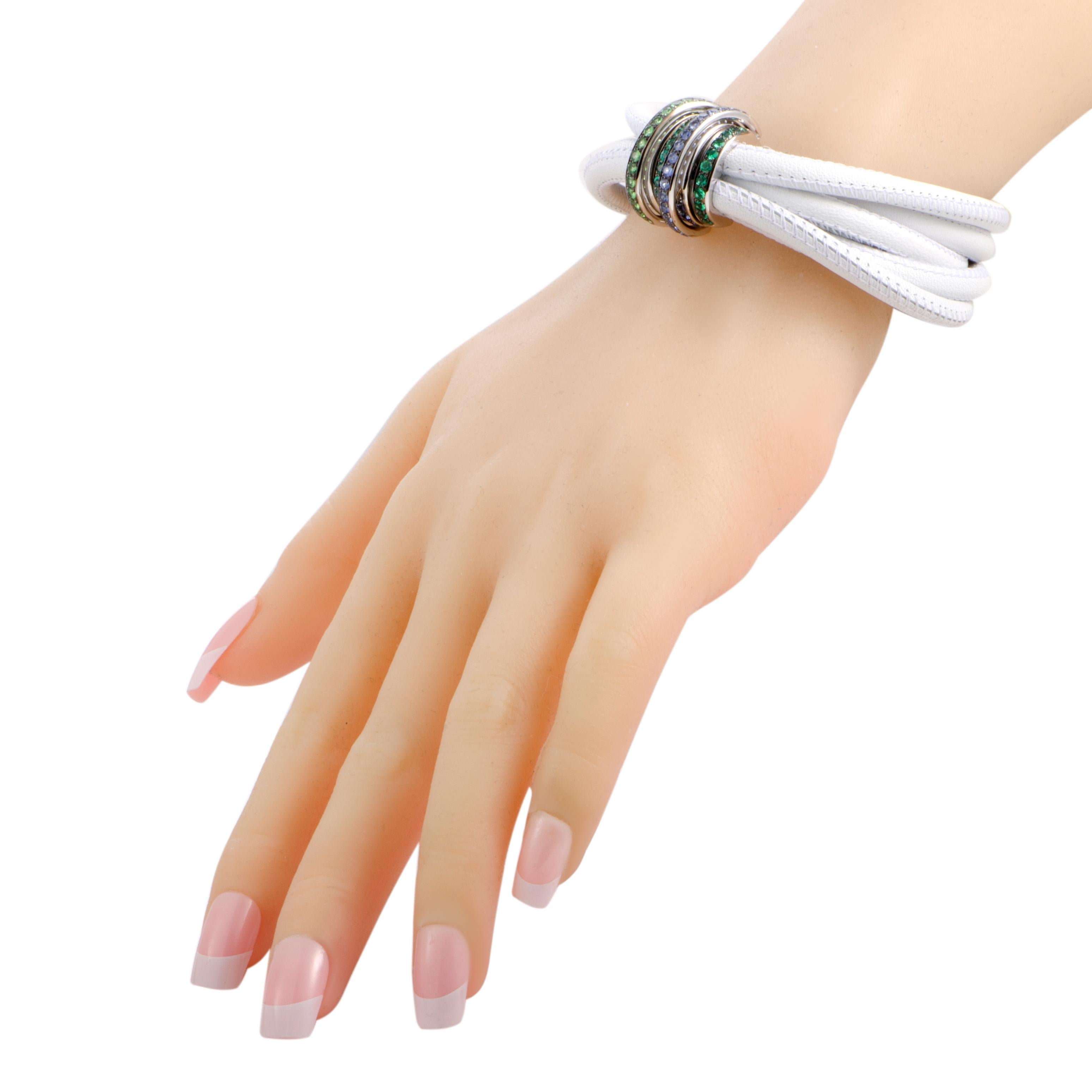 Add an incredibly stylish touch to your ensembles with this fabulous de Grisogono “Allegra” bracelet that is presented in gorgeous white leather and refined 18K white gold. The bracelet is embellished with a delightful blend of sapphires, tsavorites