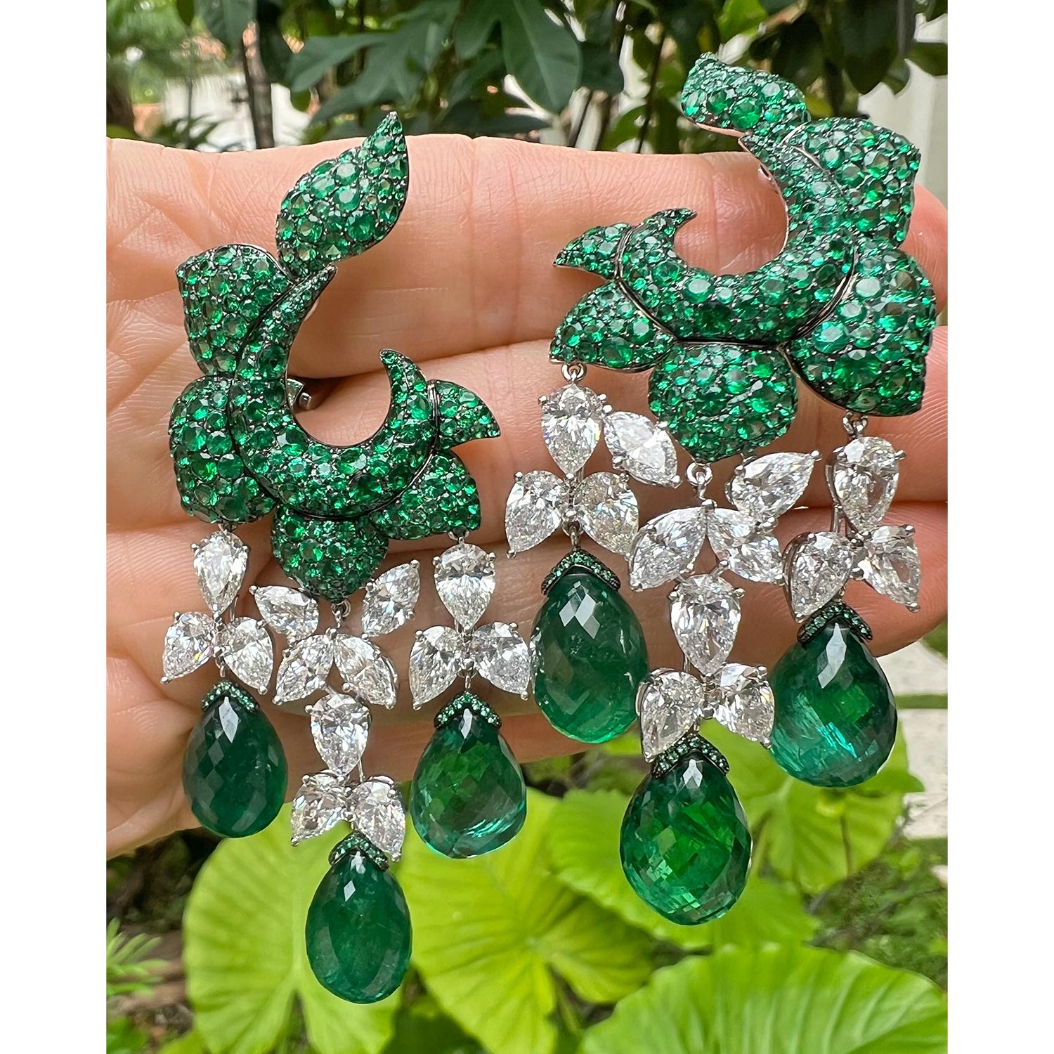 De Grisogono chandelier earrings handmade in 18k white gold and blackened 18k gold, each featuring a floral motif surmount pavé-set with emeralds suspending three drops composed of a chain of pear and marquise-shaped diamonds ending in larger