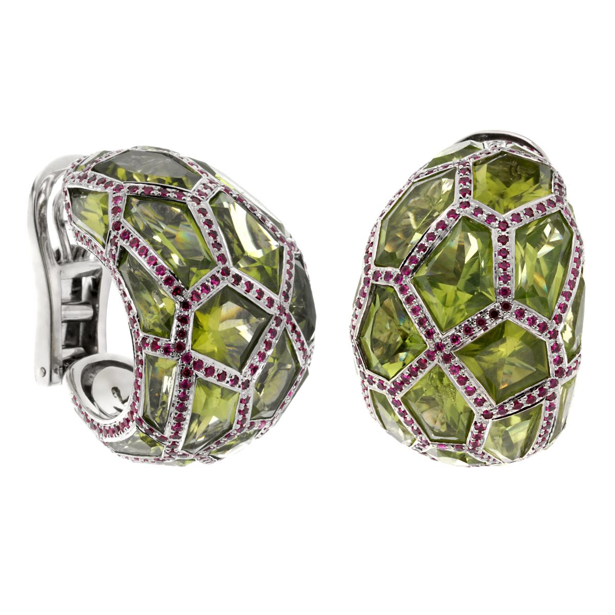 A magnificent set of De Grisogono earrings each showcasing a tapered bombe hoop design set with fancy cut peridot within a ruby-set surround honeycomb design. The earrings are 18k white gold and are signed De Grisogono, and the unique serial number.