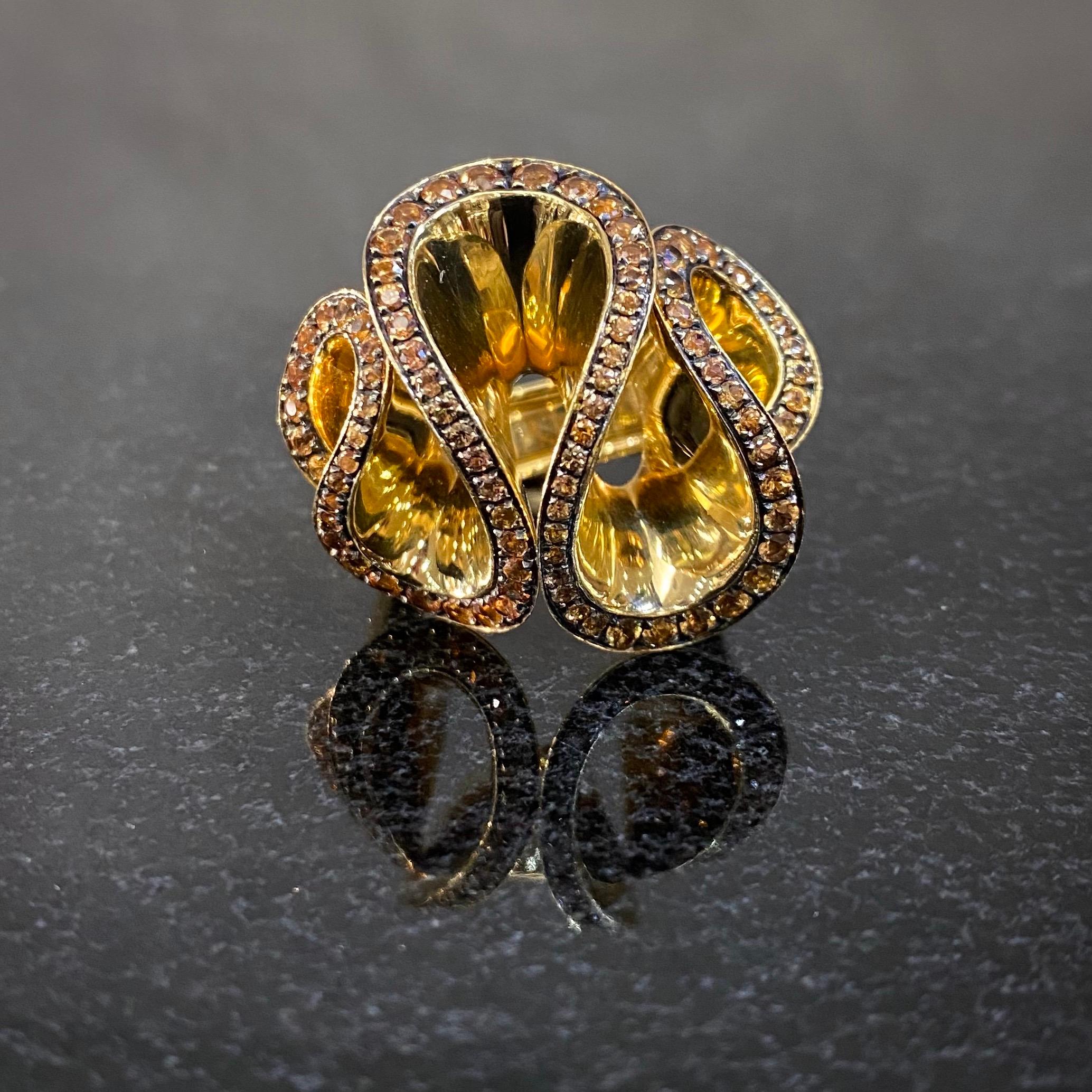 de GRISOGONO round-shape fancy-colored sapphire abstract cocktail ring in 18kt yellow gold, circa 2000. From the brand’s Zingana collection, this scrolled openwork ring of a three-dimensional serpentine shape in polished yellow gold is grain-set to