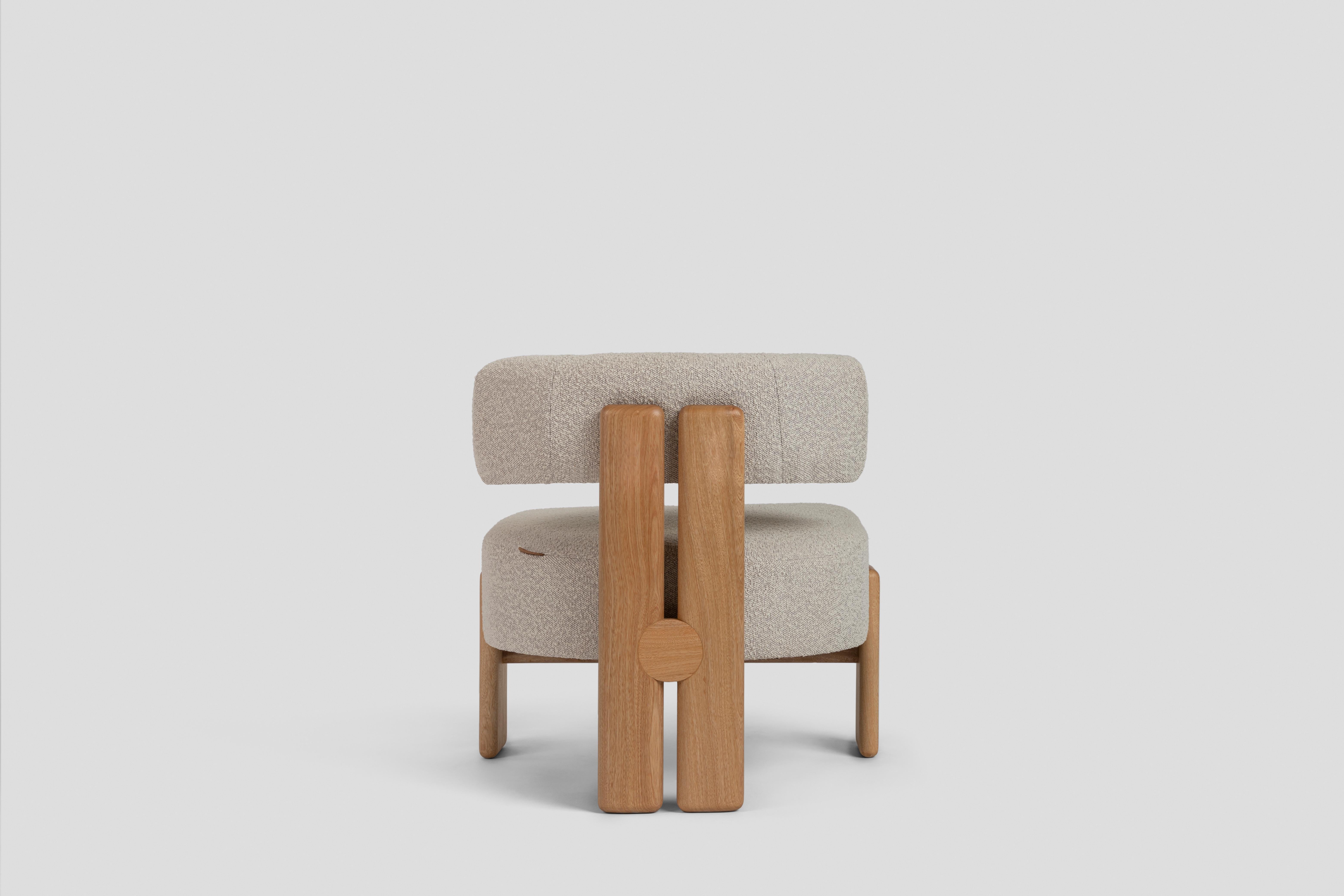 Inspiriert von dreibeinigen Stühlen, hat dieser niedrige Stuhl ein Rückenbein, das aus zwei Teilen besteht, die durch ein rundes Holzdetail verbunden sind, und zwei Seitenbeine, die die Sitzfläche umschließen. Er ist als Ergänzung in einem