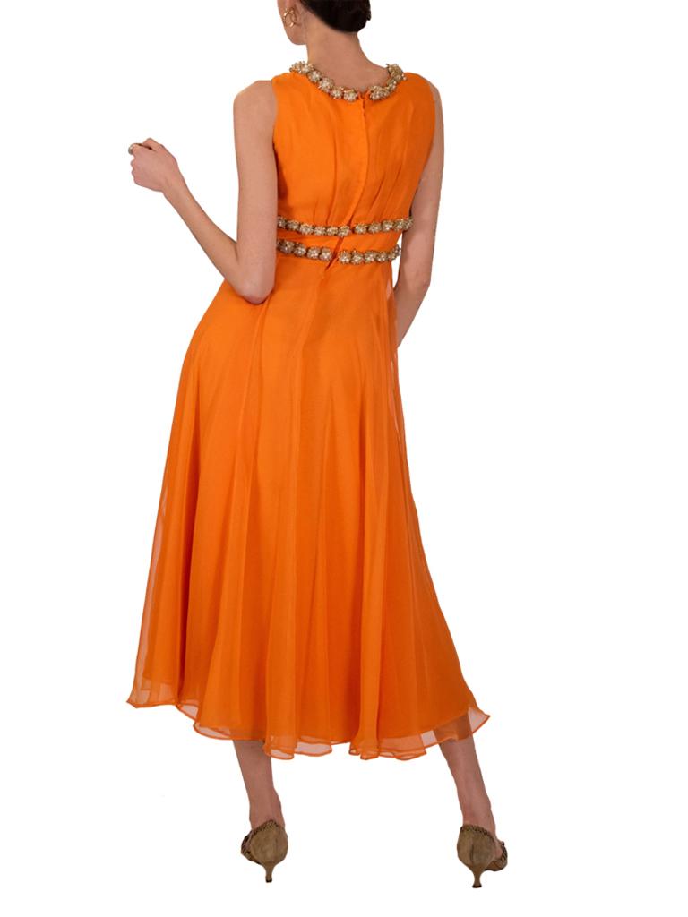 1960s orange dress, the fitted waist is accentuated with clusters of faux pearl teardrops and clear crystal flutes all accented with gold toned seed beads, forming a central loop with gathering detail. The rounded neckline is also adorned with