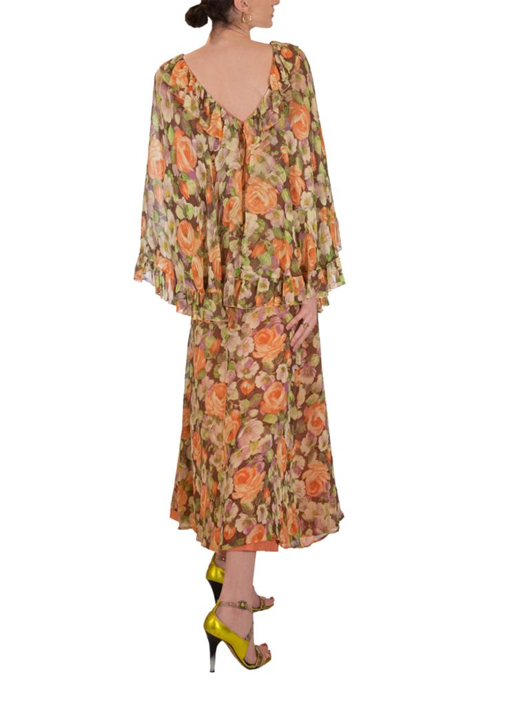 Robe florale John Charles London dans des tons d'orange, de vert, de mauve et de brun. Manches à effet cape terminées par des volants sur le bord.

1970s. Etiquette John Charles London. Taille marquée 12

Stelios Hawa a créé des robes de jour