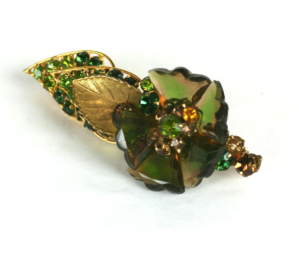 De Mario Faceted Glass Petal Flower Brooch from the 1940's. Unusual changeant green-topaz faceted Czech petals form the flower head accented by an array of green and topaz crystals all hand sewn onto a filigree base.
1940's USA. 
3