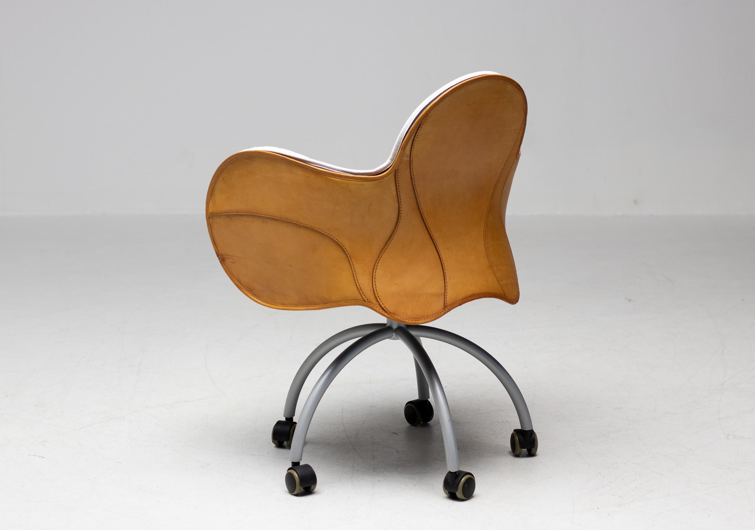 Incisa, designed by Vico Magistretti, is a swivel armchair on wheels with outer cowhide cover, like a saddle. Hand stitching adorns the back and sides, forming soft curves, precious to the touch. The comfortable padded inner covering, with cotton