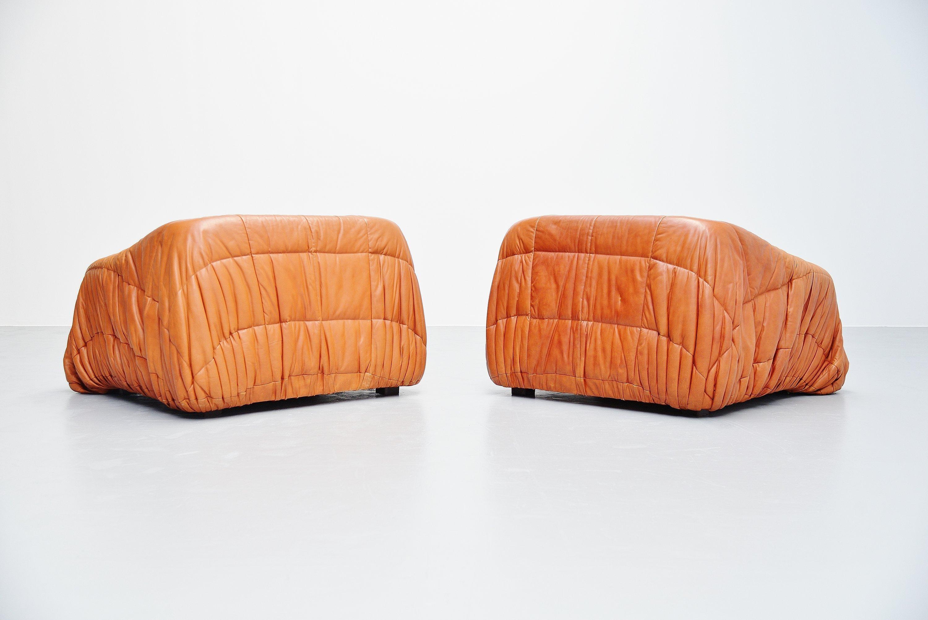 Fantastic pair of Piumino lounge chairs designed by De Pas, D'urbino and Lomazzi and manufactured by Dall'Oca, Italy, 1970. The chairs have a cognac leather upholstery which looks really nice with the wrinkled stitching pattern. The chairs have a