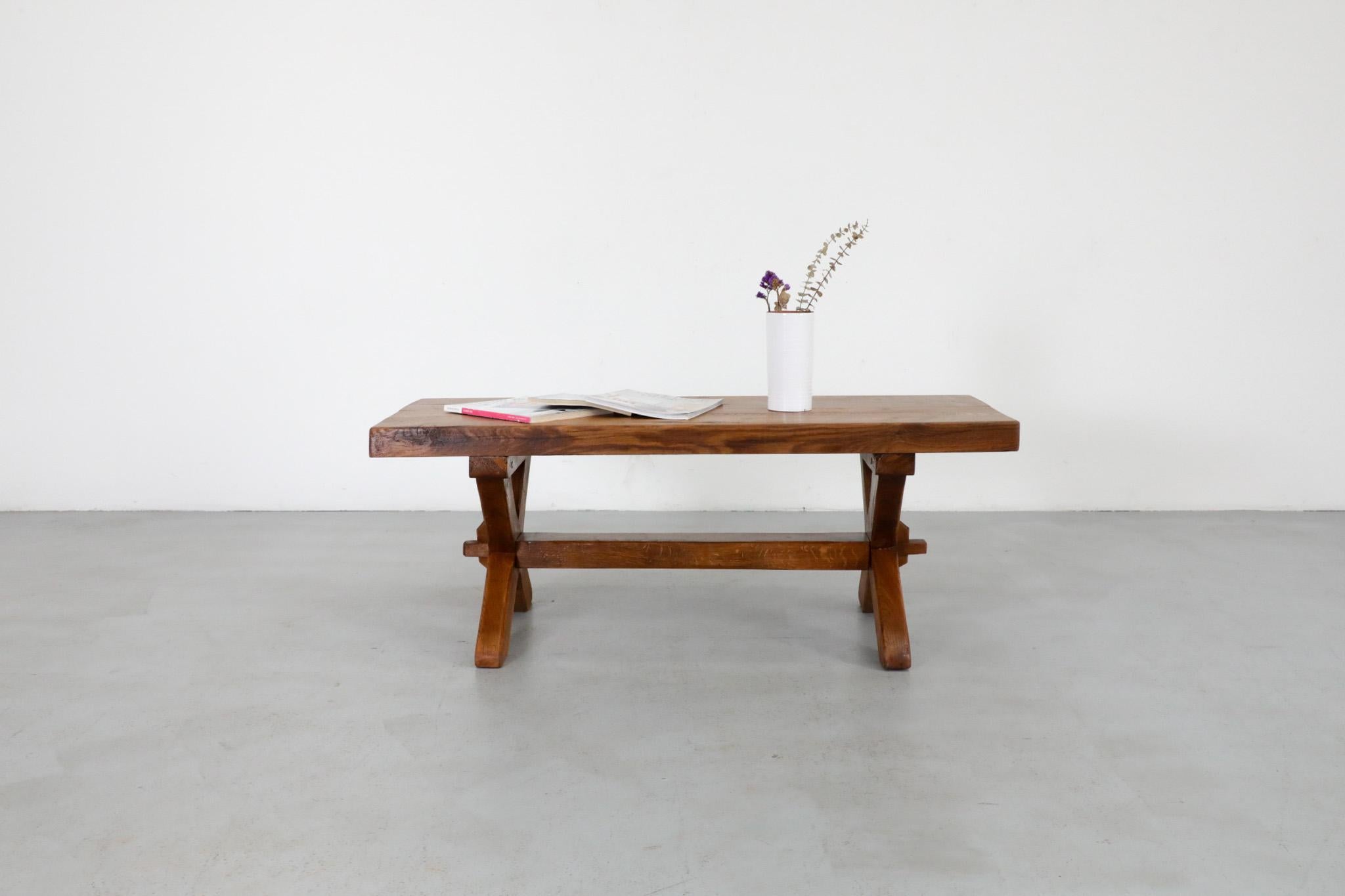 Beautiful Brutalist coffee table or bench with trestle base and peg tension construction. This table is dark stained, solid oak with gorgeous grain pattern. In original condition with wear consistent with age and use.