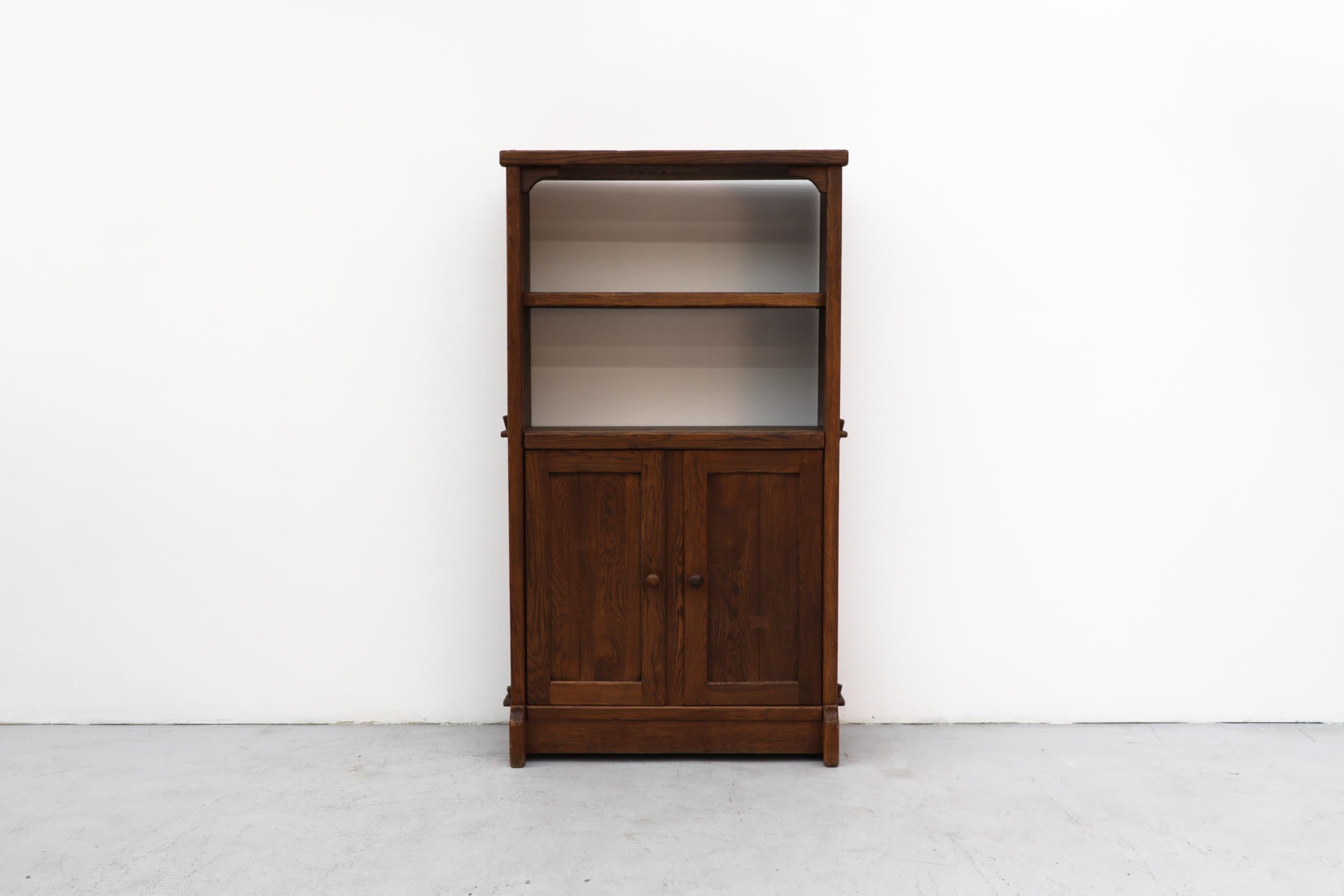 Large Brutalist oak shelving unit has shelving above and a lower cabinet. The door handle also is the latch. In original condition with wear that is consistent with its age and use. Other similar standing shelving units that are pictured, are
