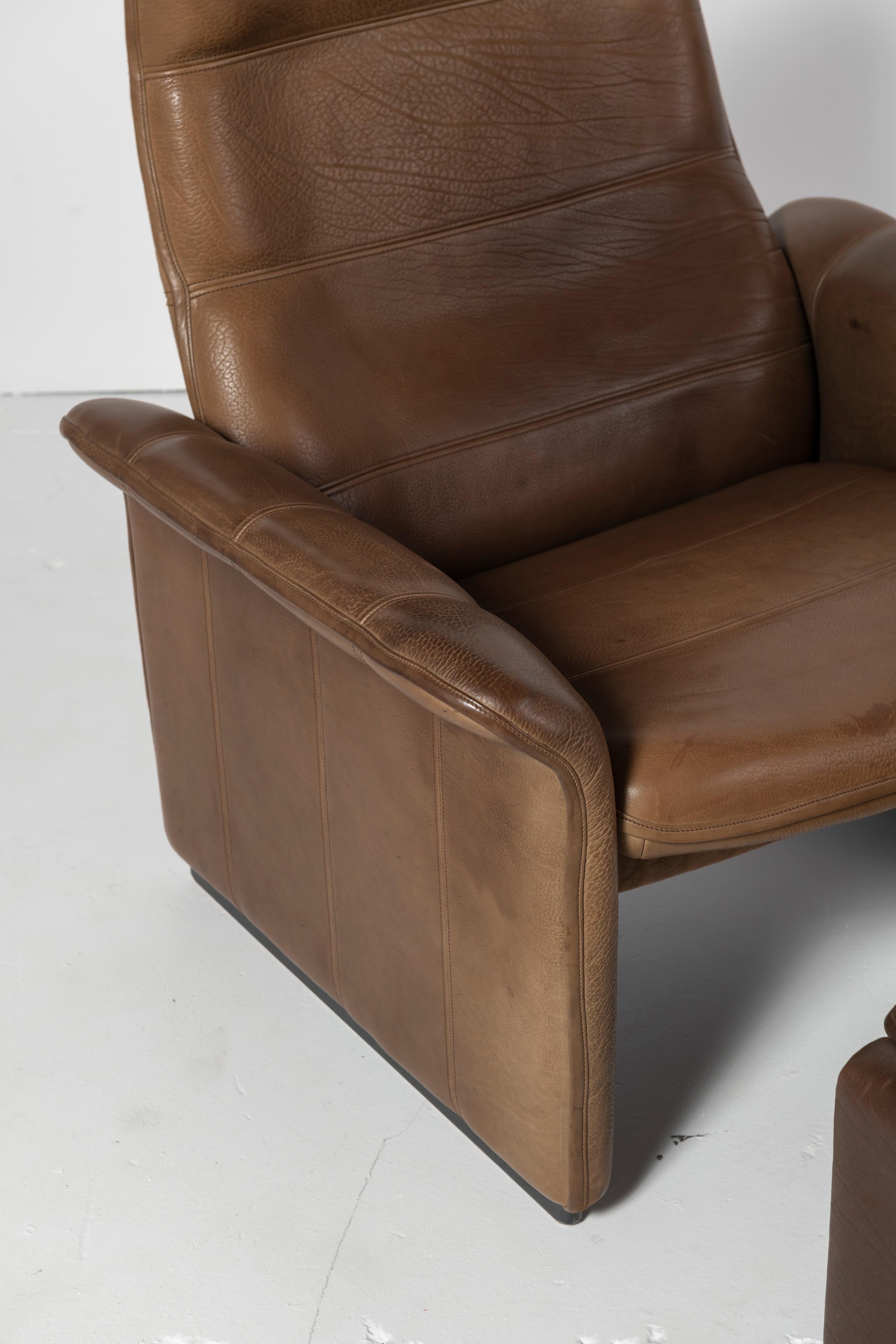 This De Sede lounge chair and ottoman is in very good condition and has a beautiful patina on the tobacco colored leather. The chair reclines for additional functionality. Modern comfort and great design make these pieces highly collectible.