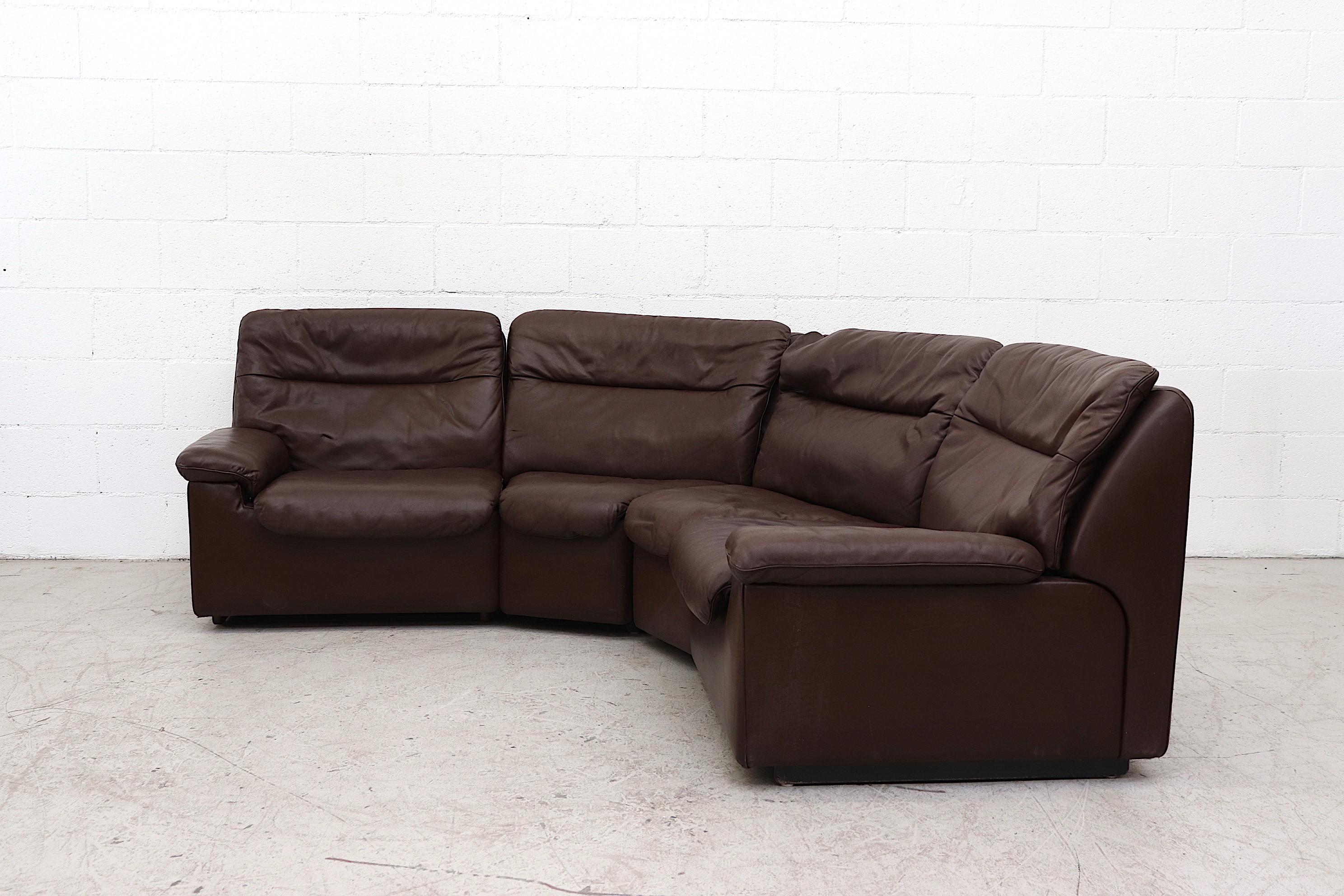 Handsome De Sede chocolate brown leather curved sectional. In good overall condition with visible patina and minor scratching to leather. Consists of 4 sections, stylish and comfortable with original manufacture print. A similar terracotta sectional