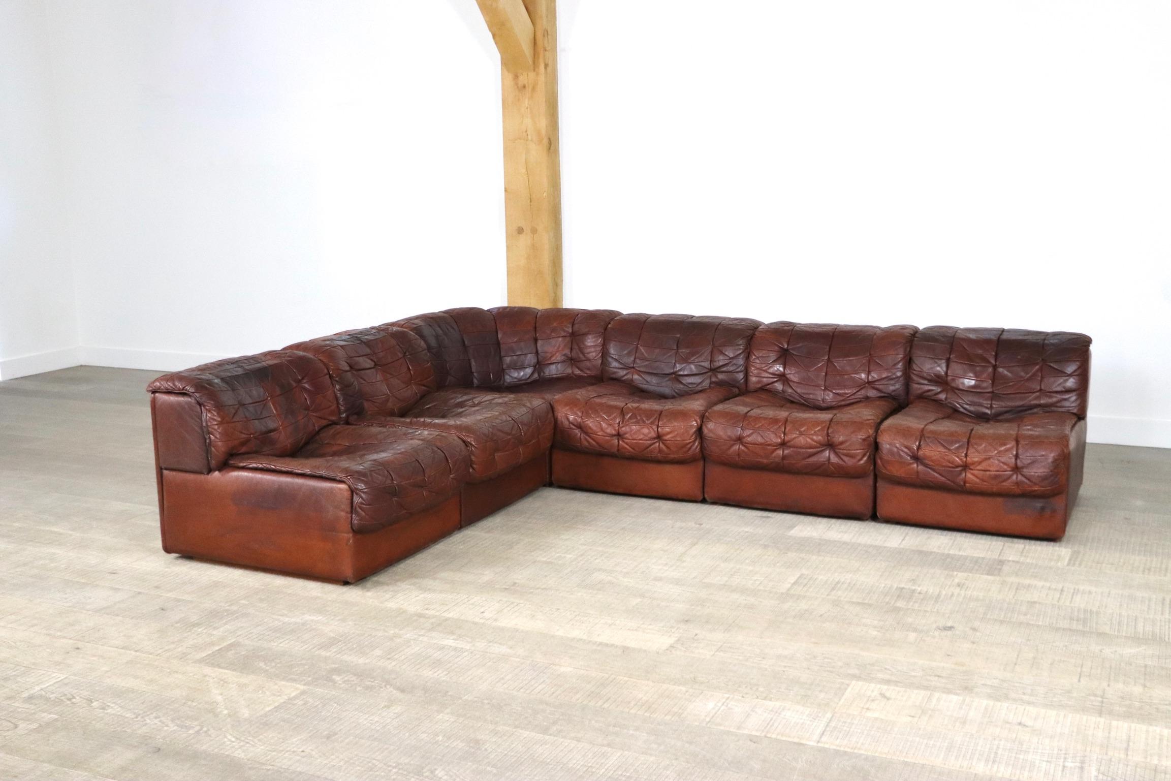 The nice modular sofa consists of 6 elements in beautifully patinated deep cognac patchwork leather. 
De Sede is famous for their use of only the best types and quality of leather, and this is why their sofas are still popular and in good condition